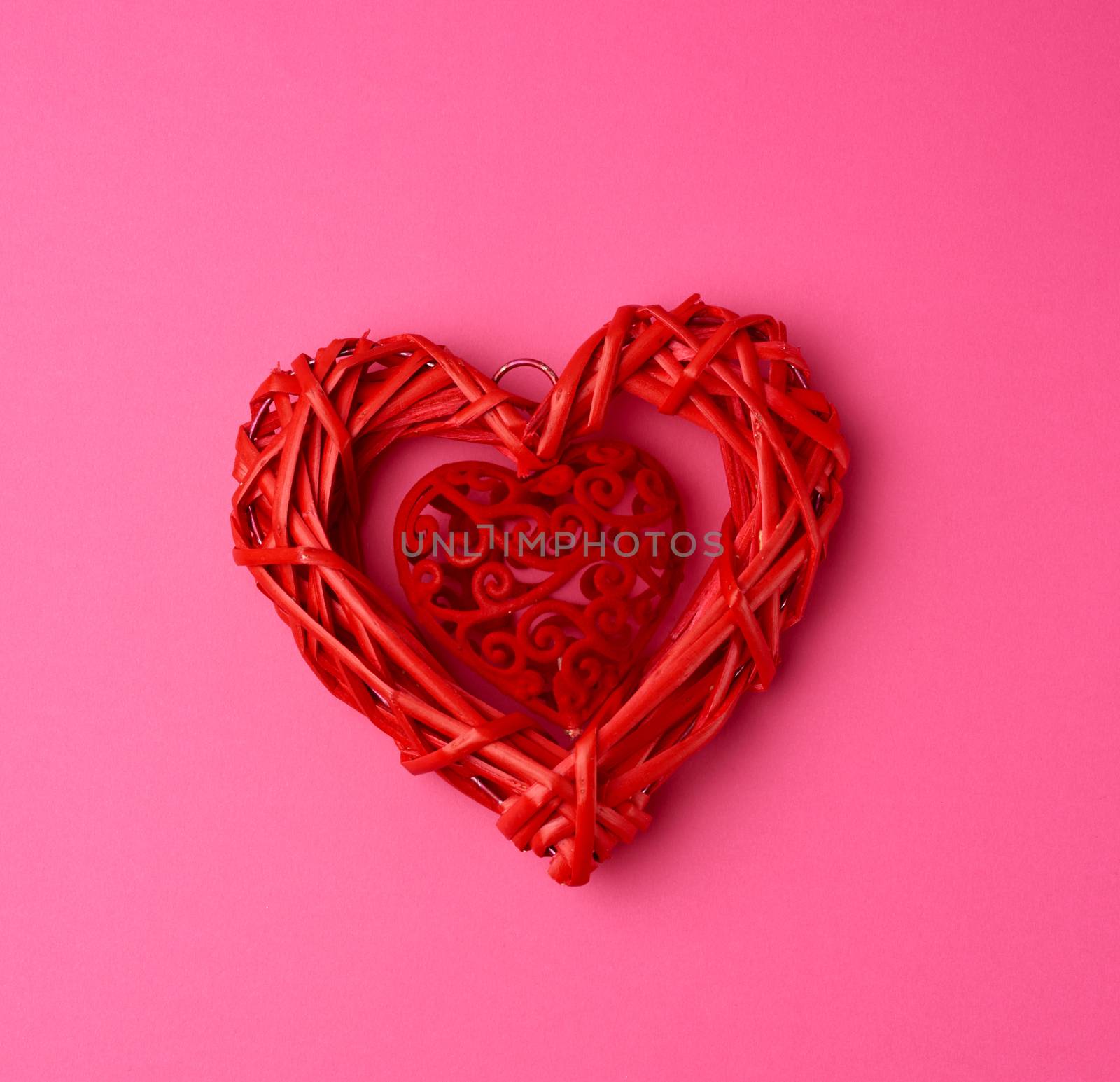 red wicker decorative heart on a pink background, festive backdrop, top view