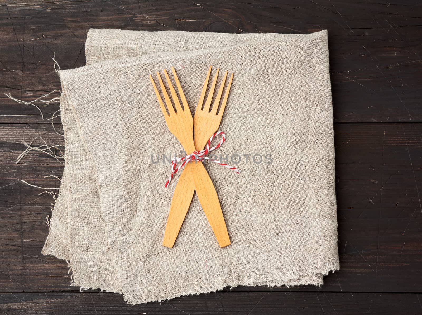 two wooden forks are tied with a rope and lie on a brown wooden  by ndanko