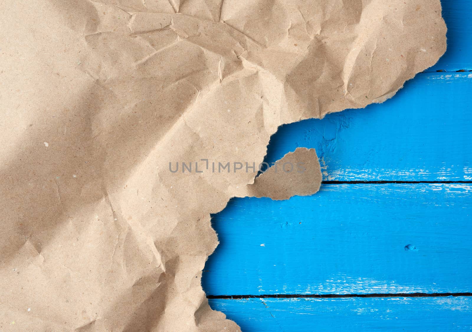 torn piece of paper on blue wooden background, copy space