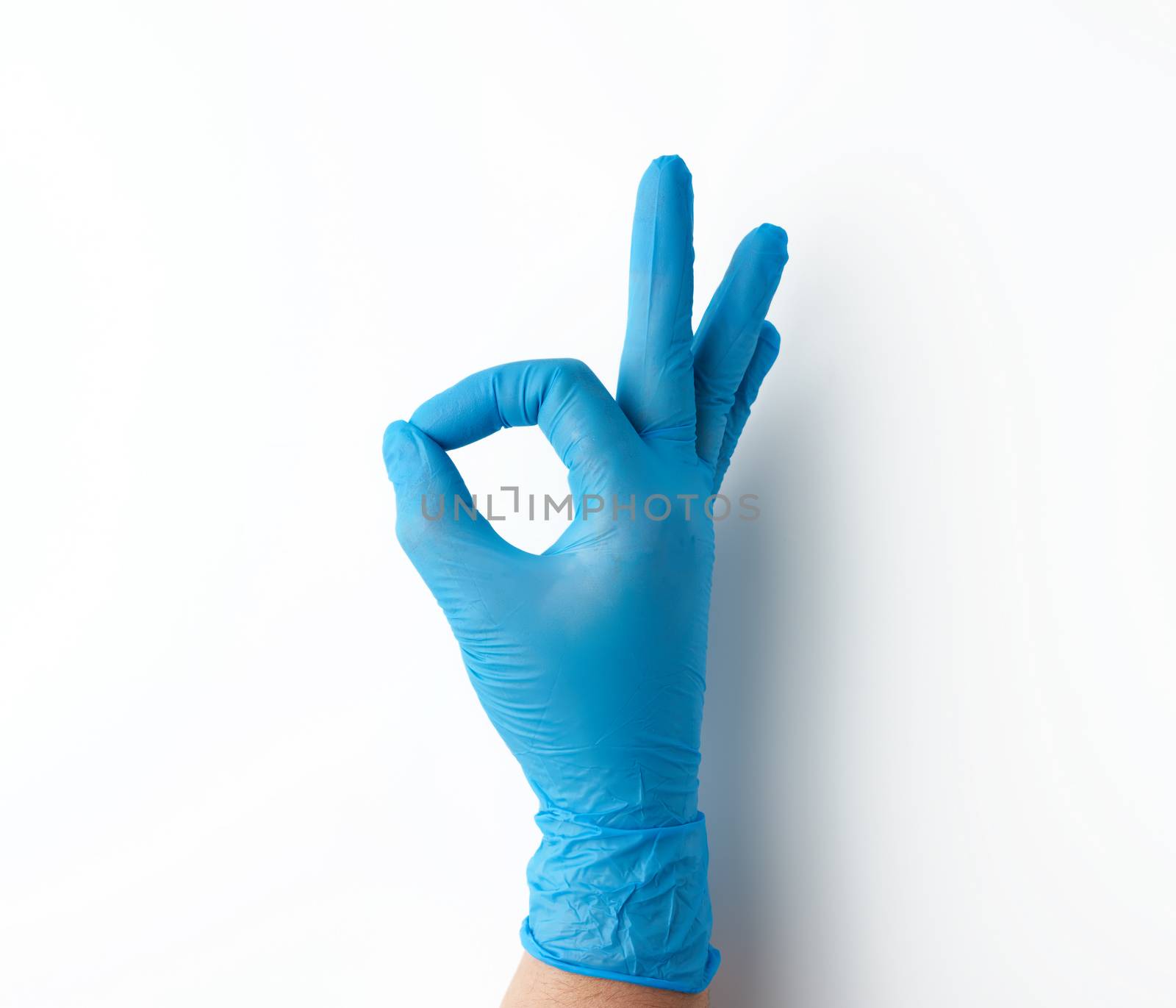 hand in blue medical glove shows ok gesture, white background, approval concept