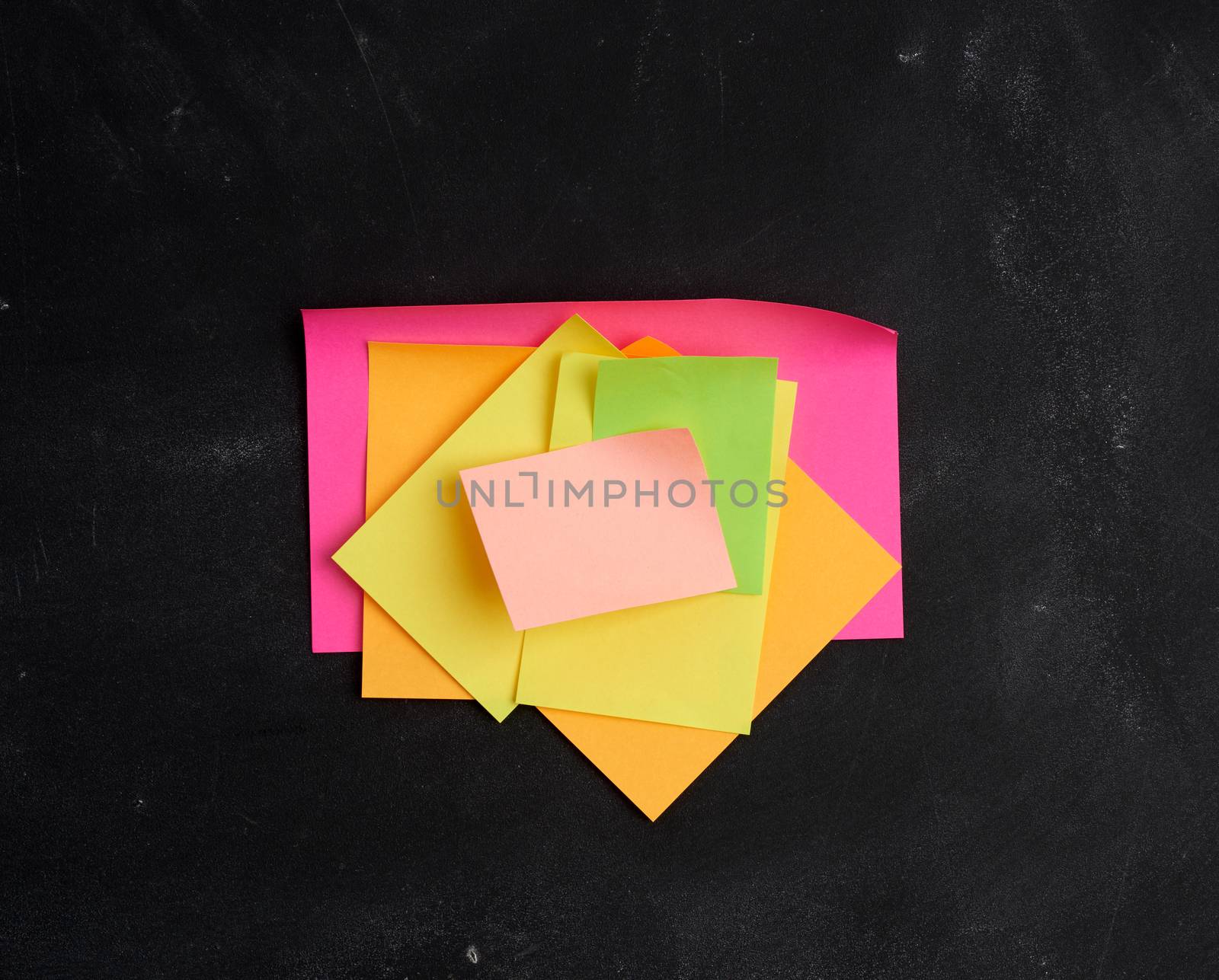 empty paper multi-colored stickers are glued on a black board by ndanko