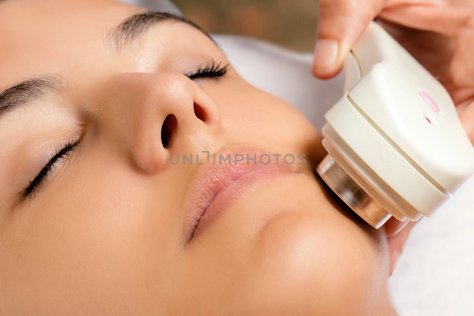 Macro close up portrait of woman having revitalizing ultrasonic skin tightening treatment in spa.
