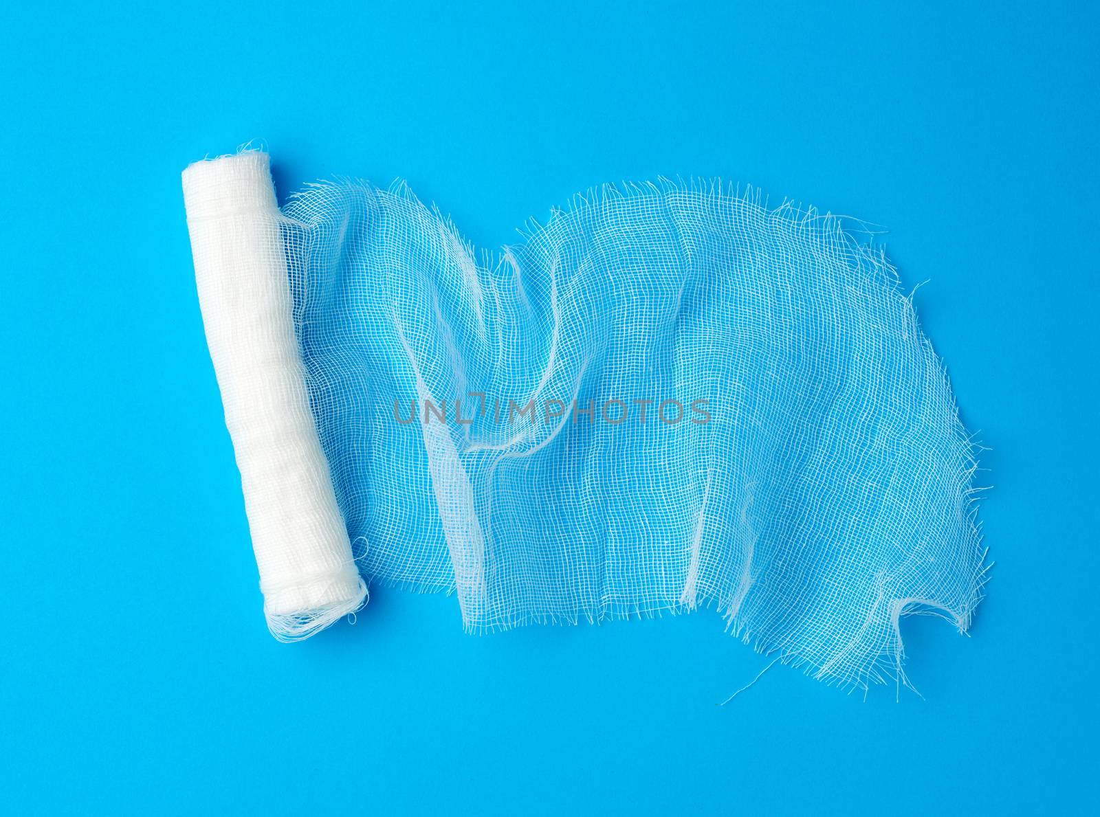 roll of white gauze bandage on a blue background, medical item for dressing human limbs
