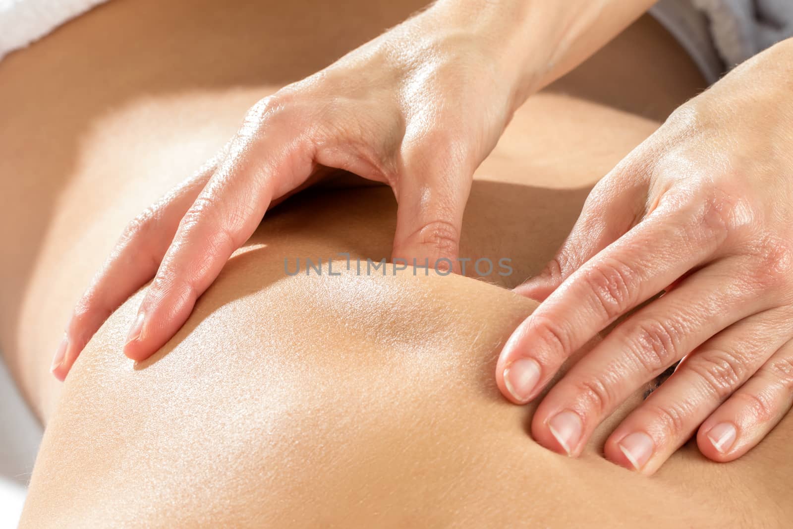 Detail of hands massaging shoulder blade. by karelnoppe
