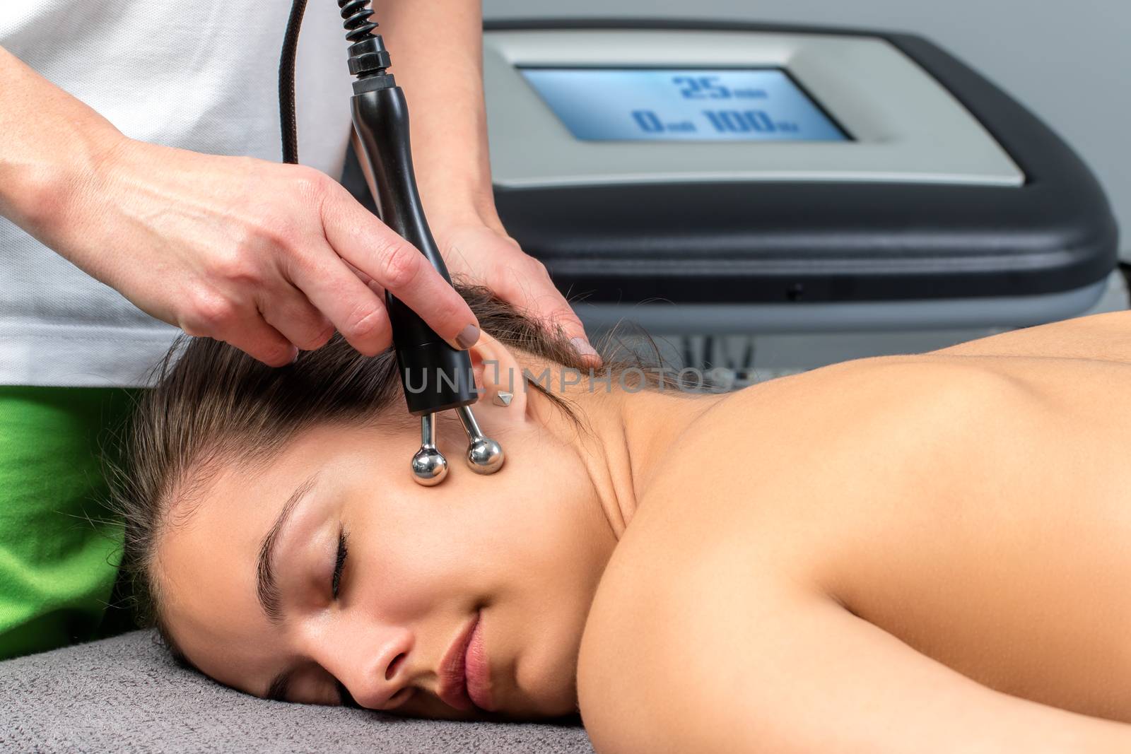 Close up of young woman receiving electrotherapy on face.Therapist stimulating nerves and muscles on cheek.