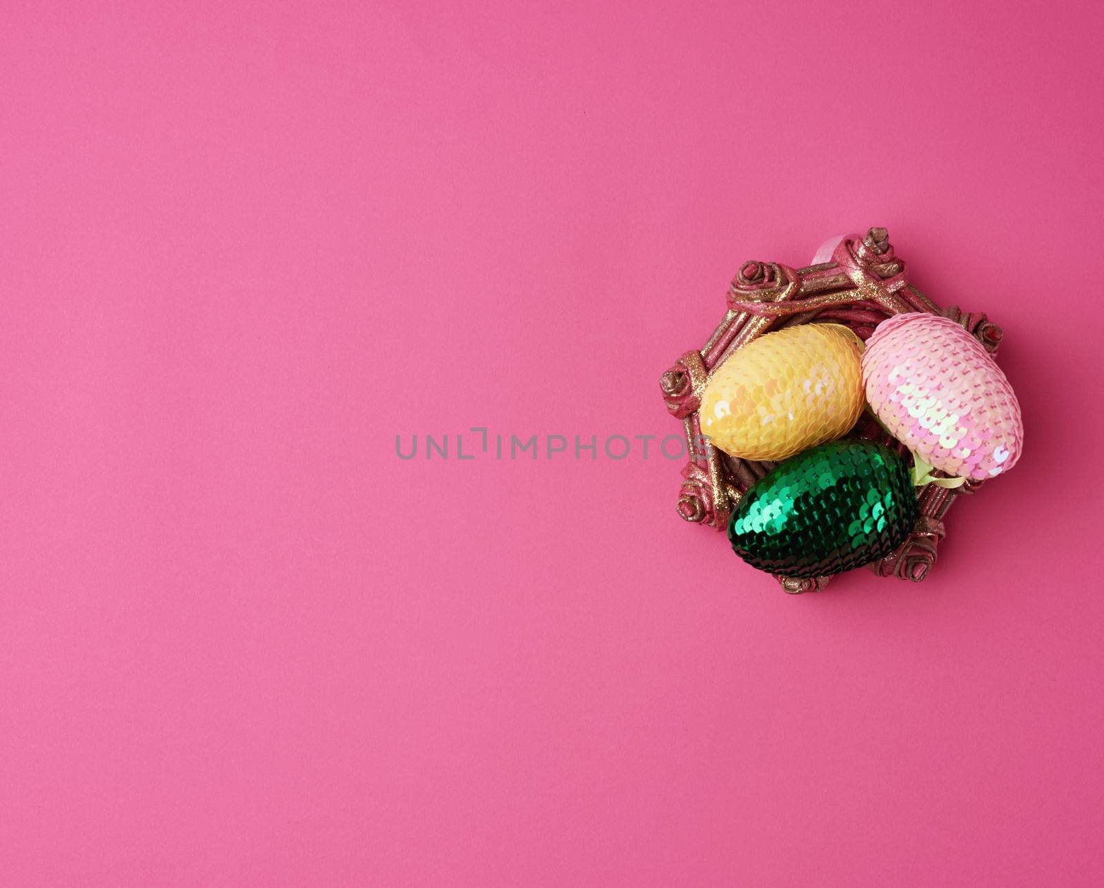 multicolored decorative Easter eggs decorated with sequins on a pink background, festive  background, top view, copy space