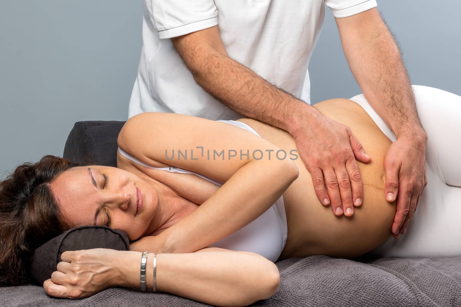 Male therapist doing physical belly treatment on pregnant woman. by karelnoppe