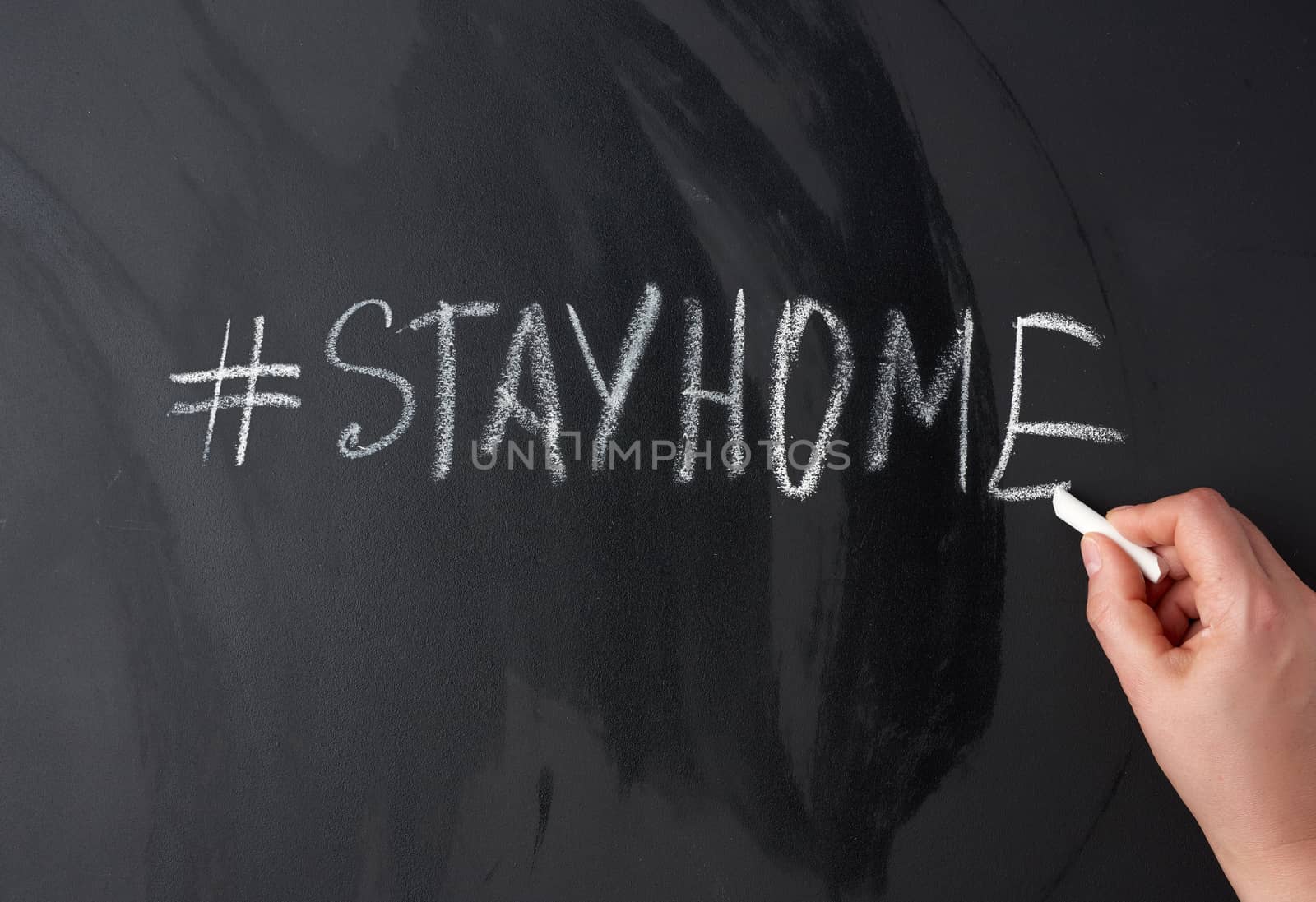 inscription stay home in chalk with a hashtag on a black chalk board, concept of self-isolation in an epidemic and pandemic