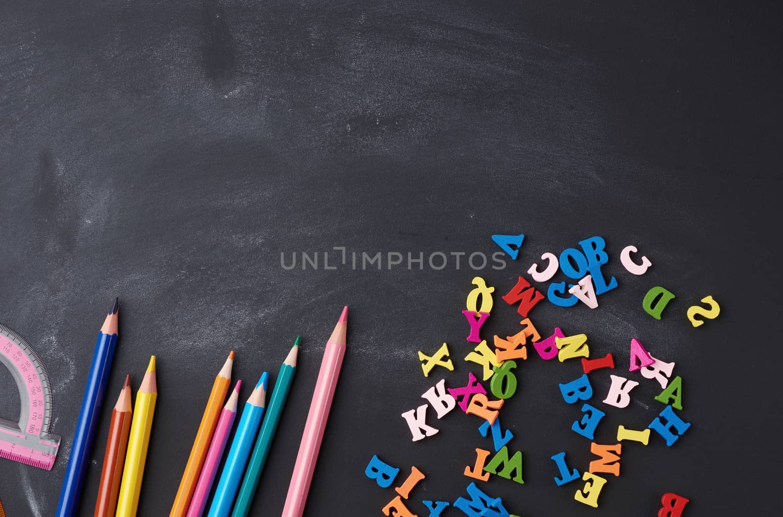 wooden multi-colored pencils, letters on a black wooden board, concept of learning, back to school, copy space