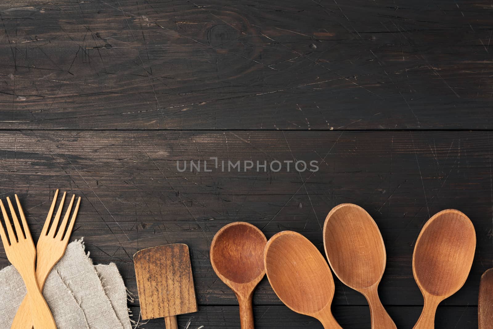 empty wooden spoons, forks and spatulas on a brown wooden background from boards, top view, kitchen background