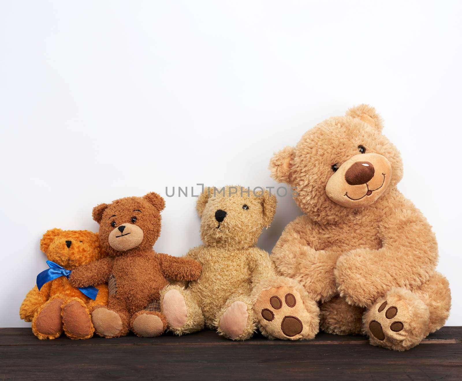 various brown teddy bears are sitting on a brown wooden table, white background, friendship concept