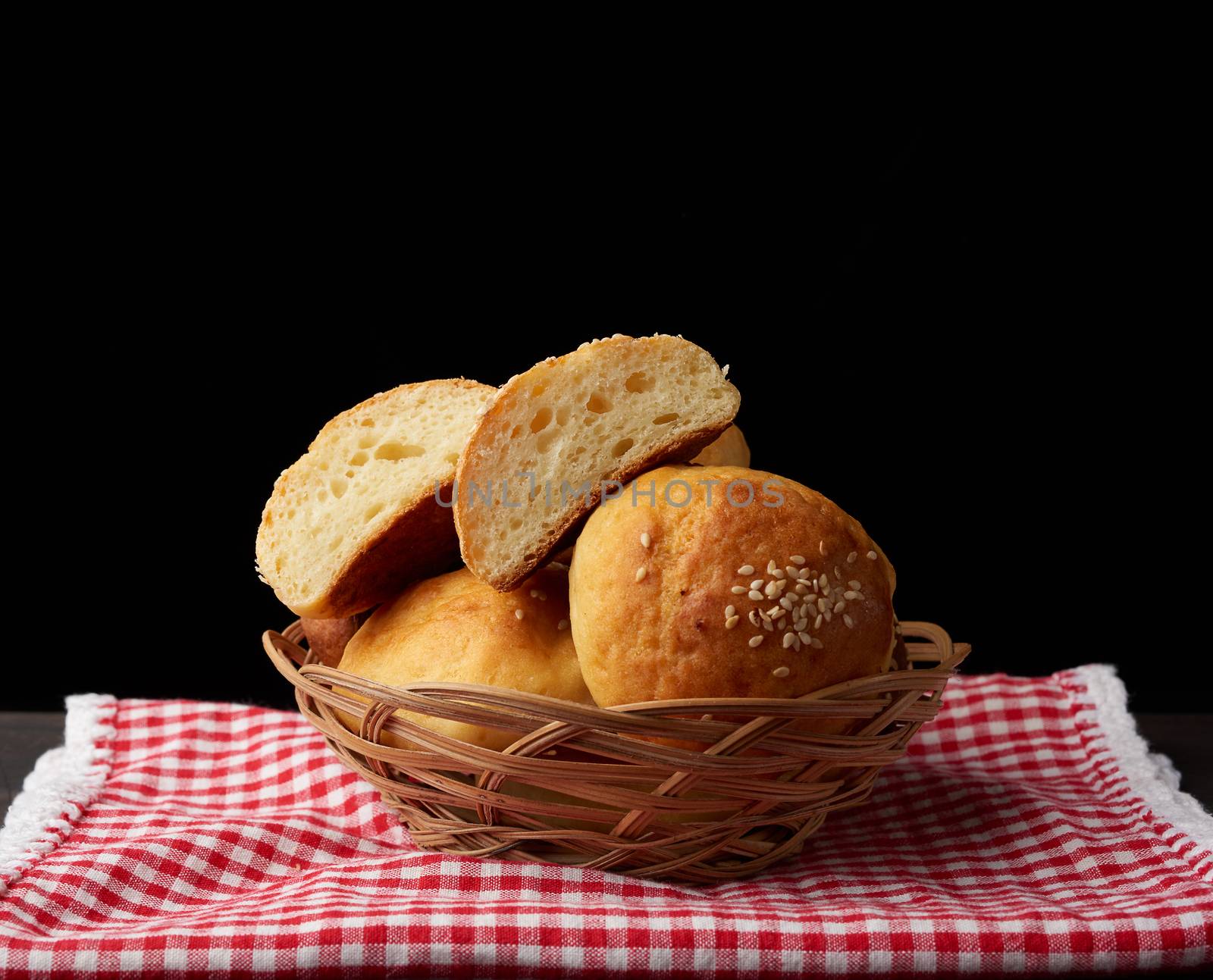 baked round bun with sesame seeds, black background, home baking