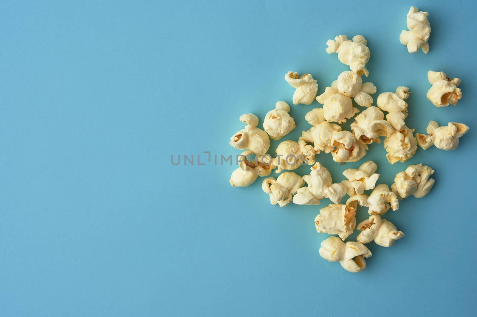 white delicious popcorn on a blue background, a place for an ins by ndanko