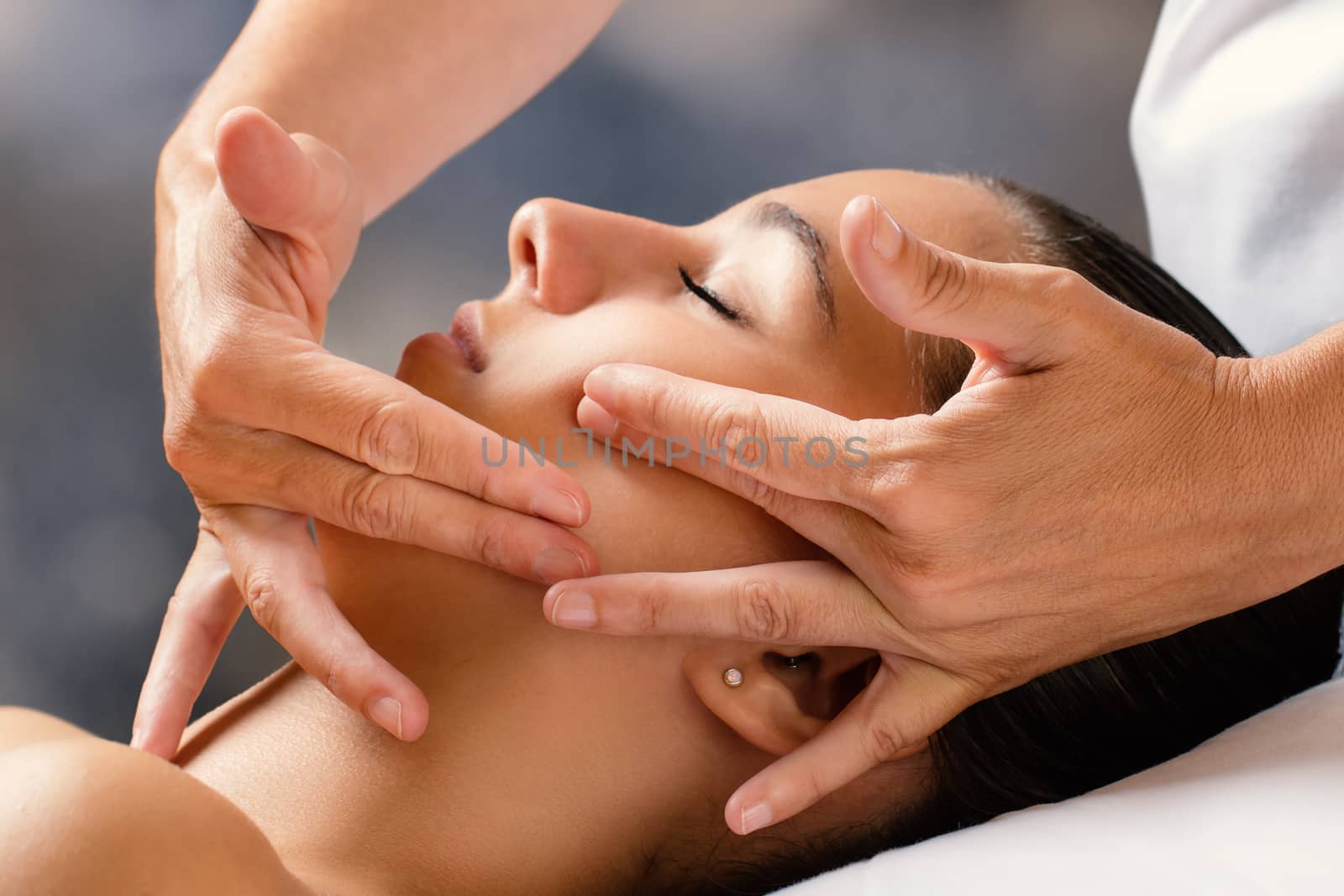 Close up portrait of woman having facial cosmetic therapy. Therapist applying cream on female cheek.