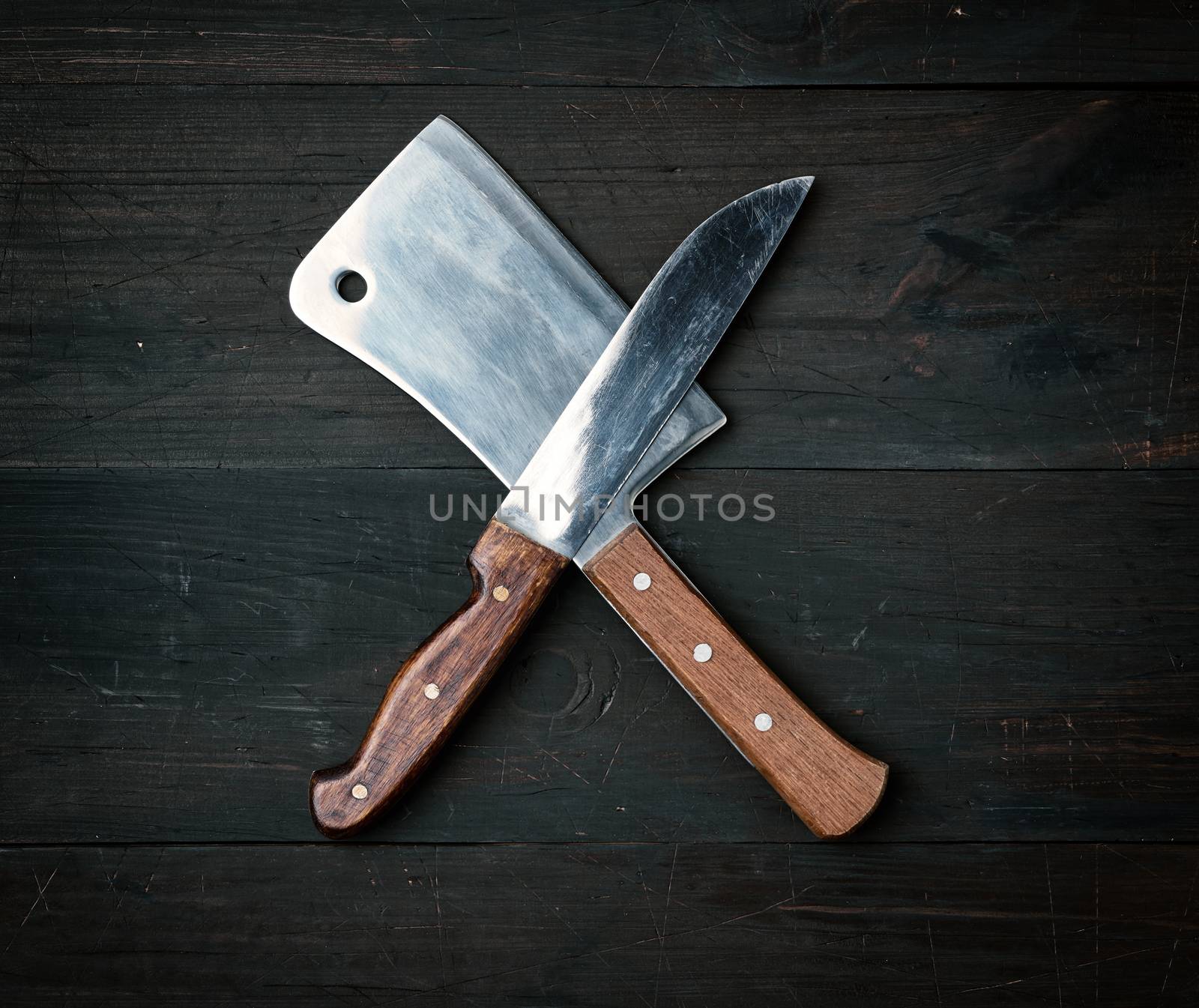 two sharp knives lie on a brown wooden surface, kitchen items ar by ndanko