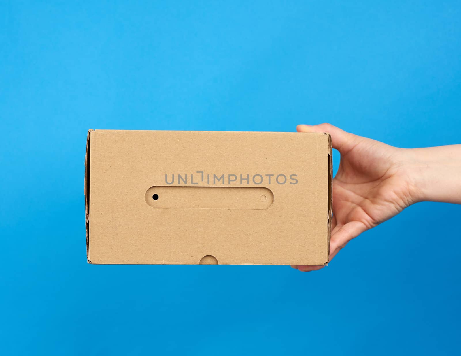 hand holds a brown cardboard box of paper on a blue background by ndanko