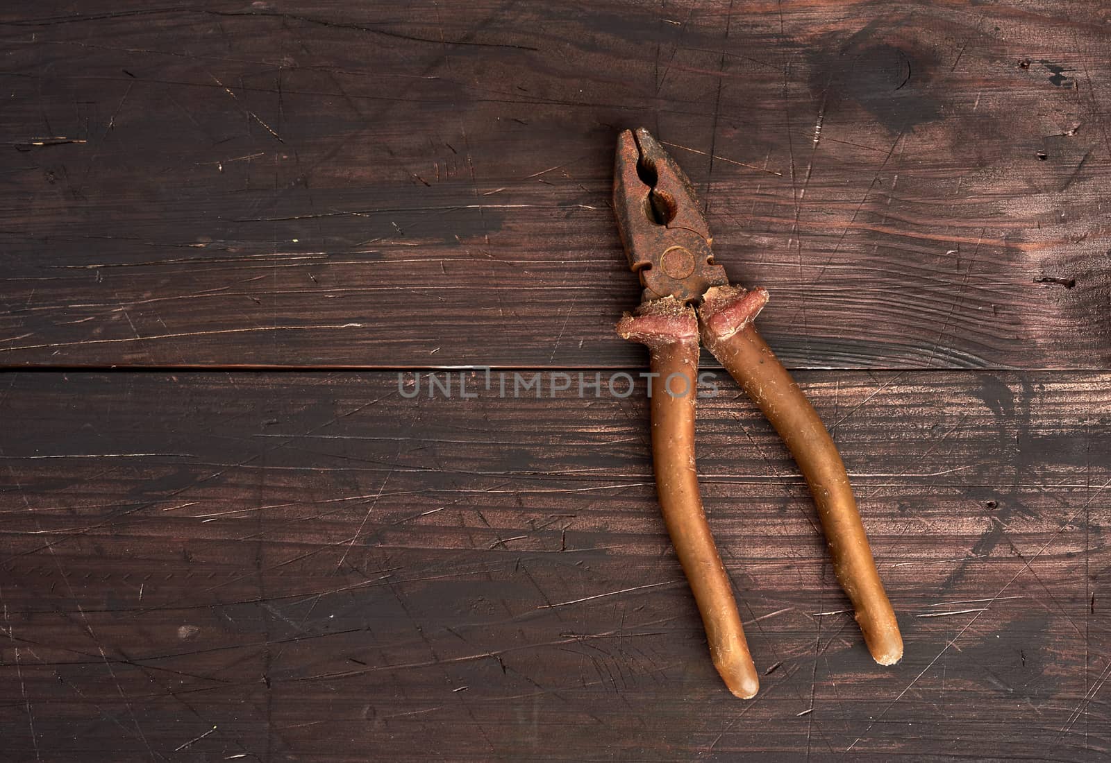 old vintage pliers on a brown wooden background by ndanko