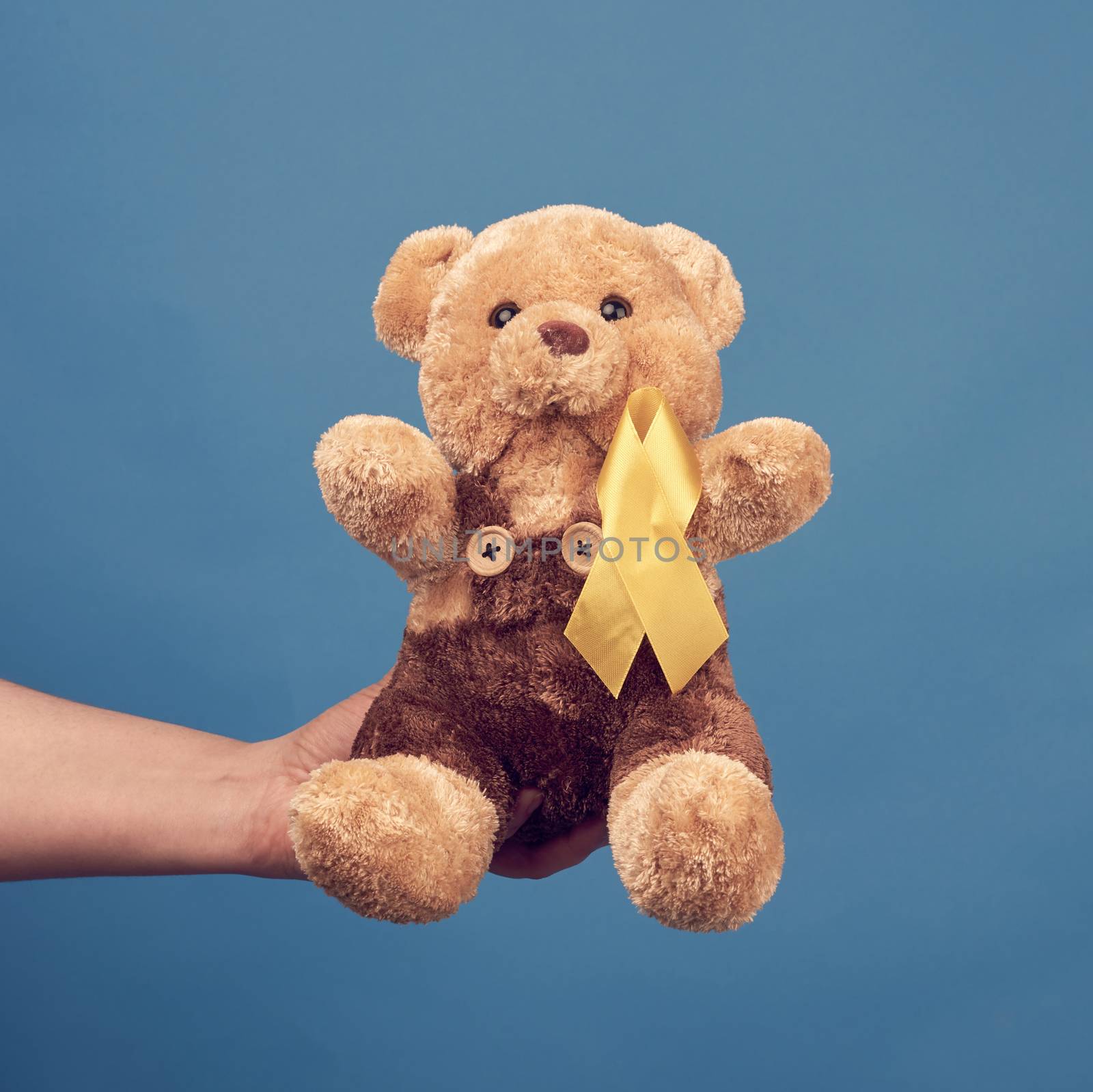 female hand hold a small teddy bear with a yellow ribbon folded by ndanko