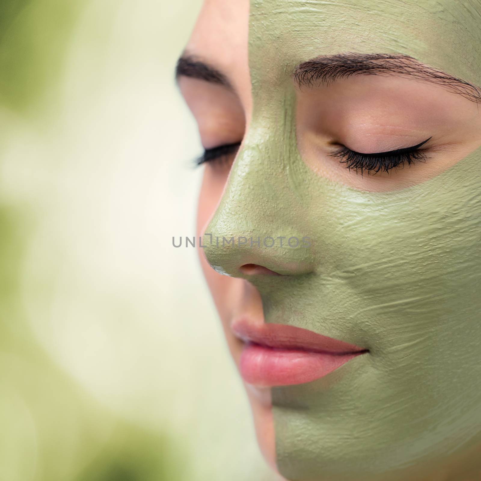 Macro  close up portrait of facial green algae cleansing mask on young woman.