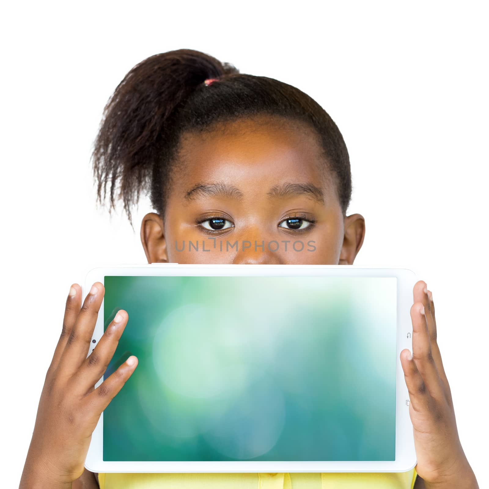 Close up fun portrait of cute little african girl with ponytail peeking behind digital tablet. Kid holding and showing blank digital screen.