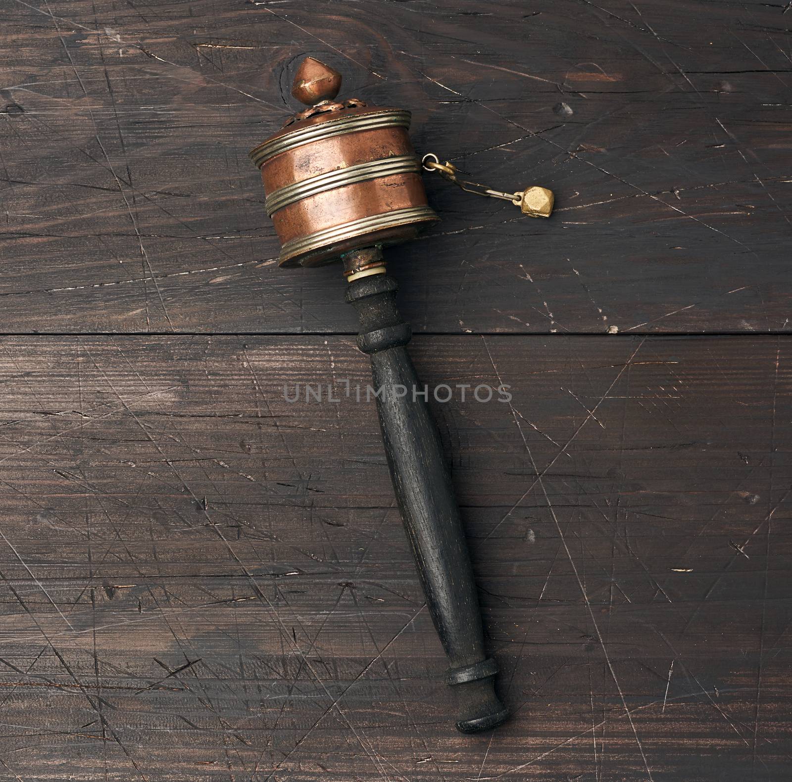 copper Tibetan prayer drum on a brown wooden background, top view