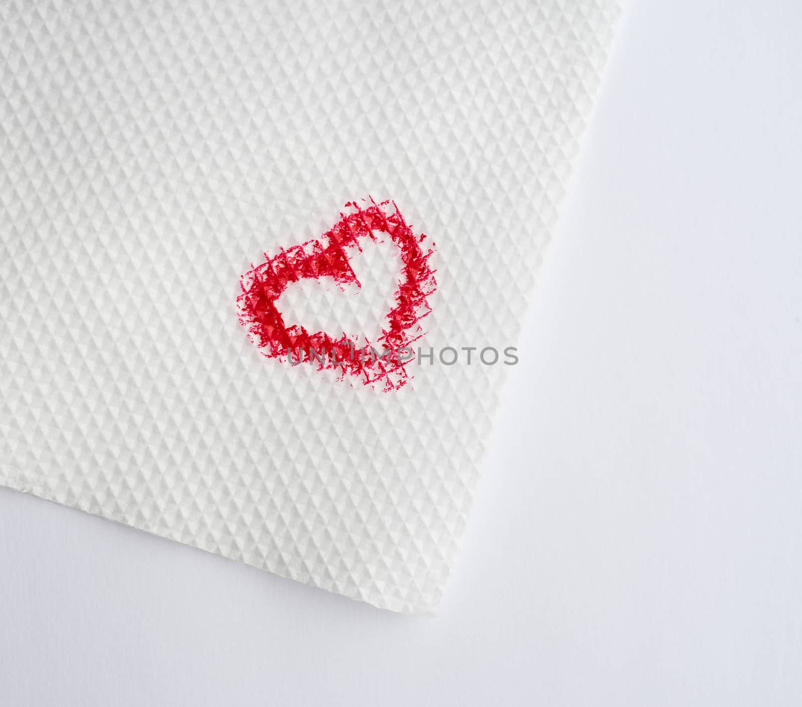 painted heart with red lipstick on a white paper napkin, close up