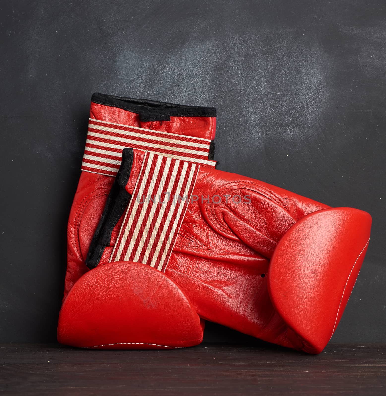 pair of red leather boxing gloves on a black background, sports equipment, close up