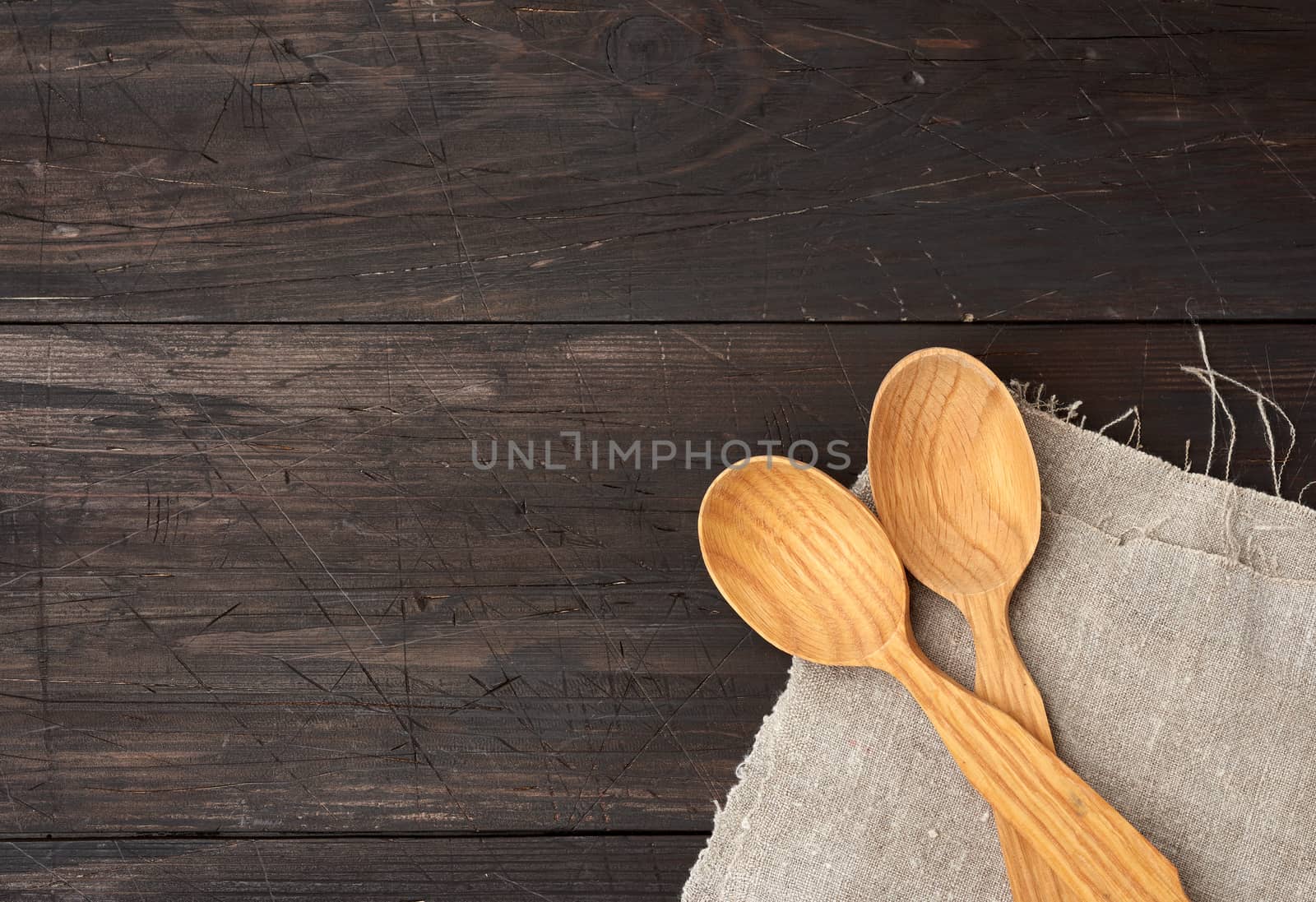 two empty wooden spoons on a brown wooden background from boards, top view, copy space