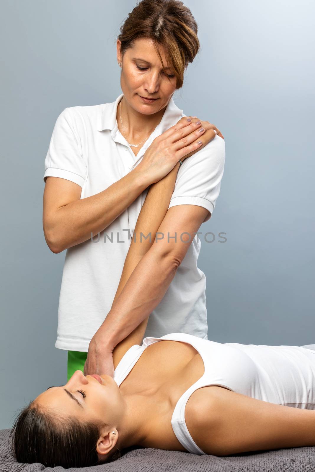 Close up of female physiotherapist doing arm and shoulder treatment on patient.
