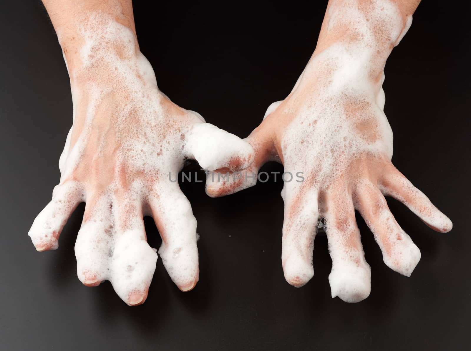 female hands in white soap suds on a black background, concept of washing hands against bacteria, body care, top view
