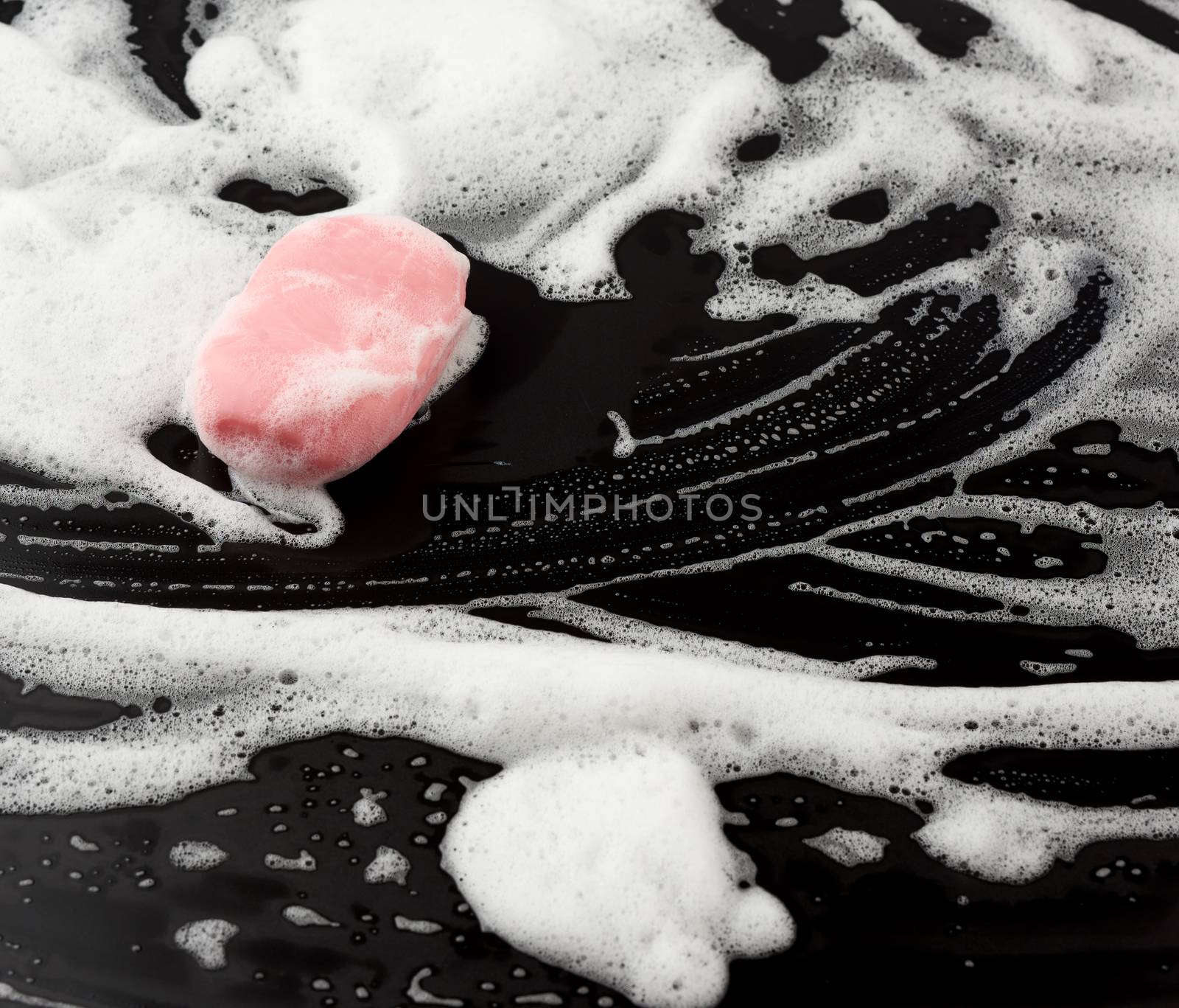 white soap foam and pink soap on a black background, top view by ndanko