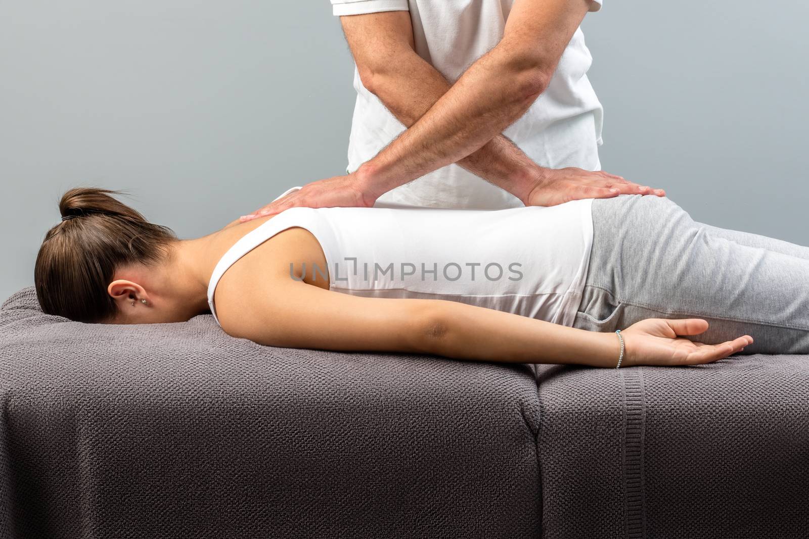 Close up of male physiotherapist doing manipulative massage on young woman.