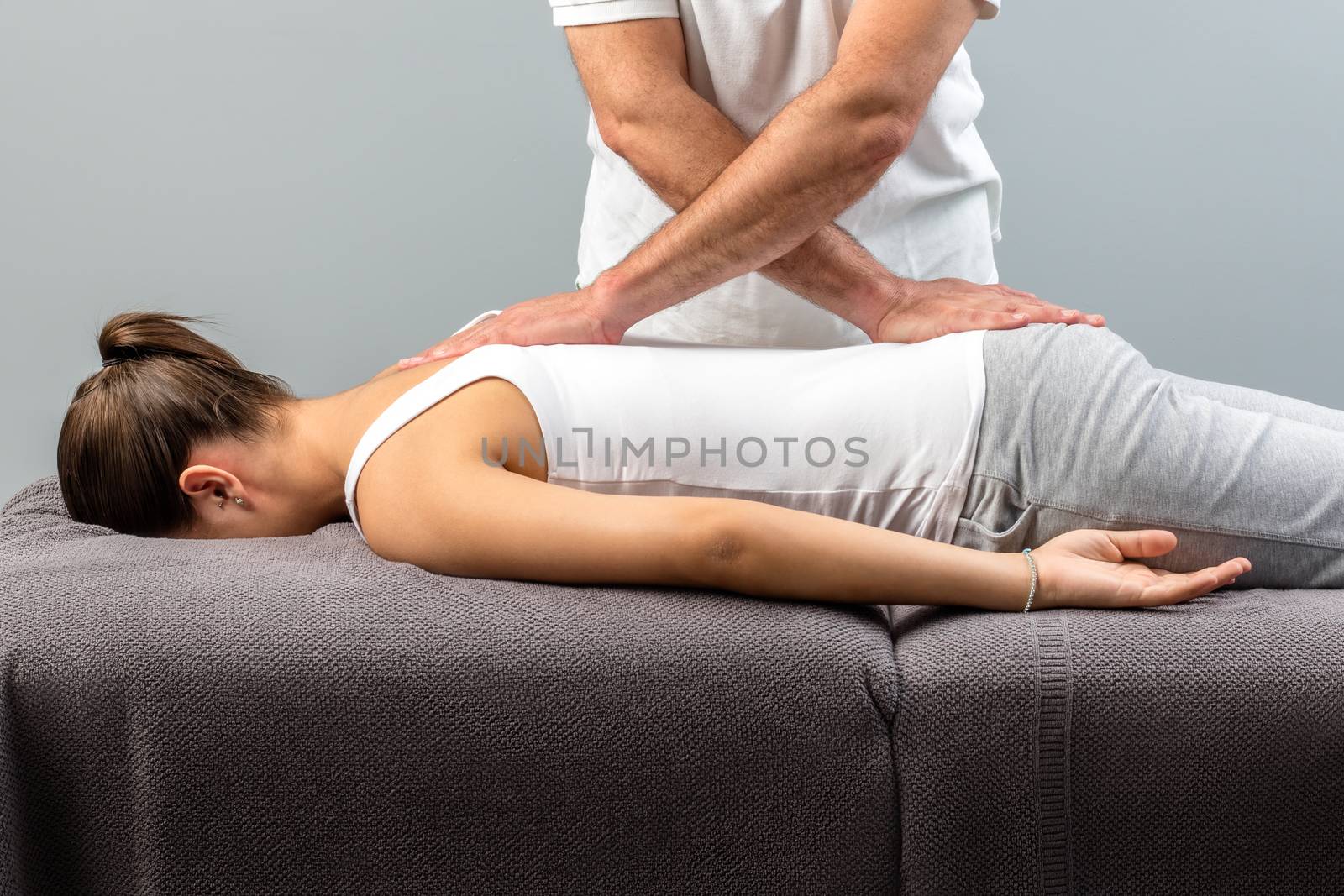 Male osteopath doing back massage on young woman. by karelnoppe