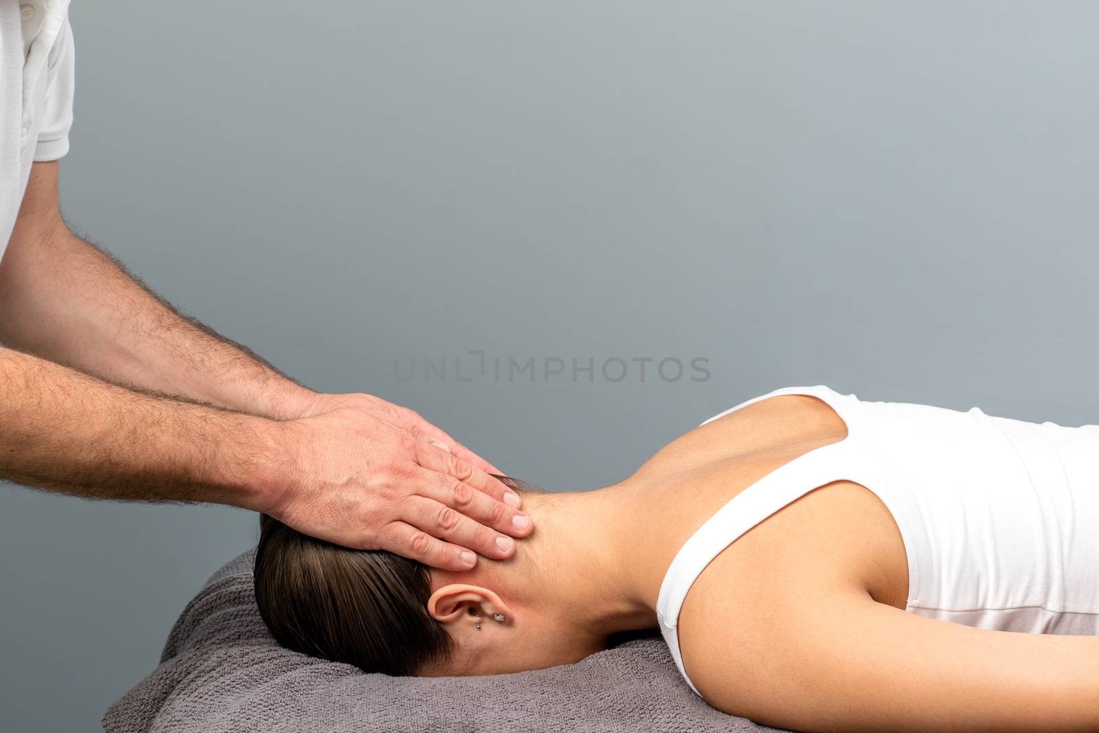 Therapist applying pressure on back of female head. by karelnoppe