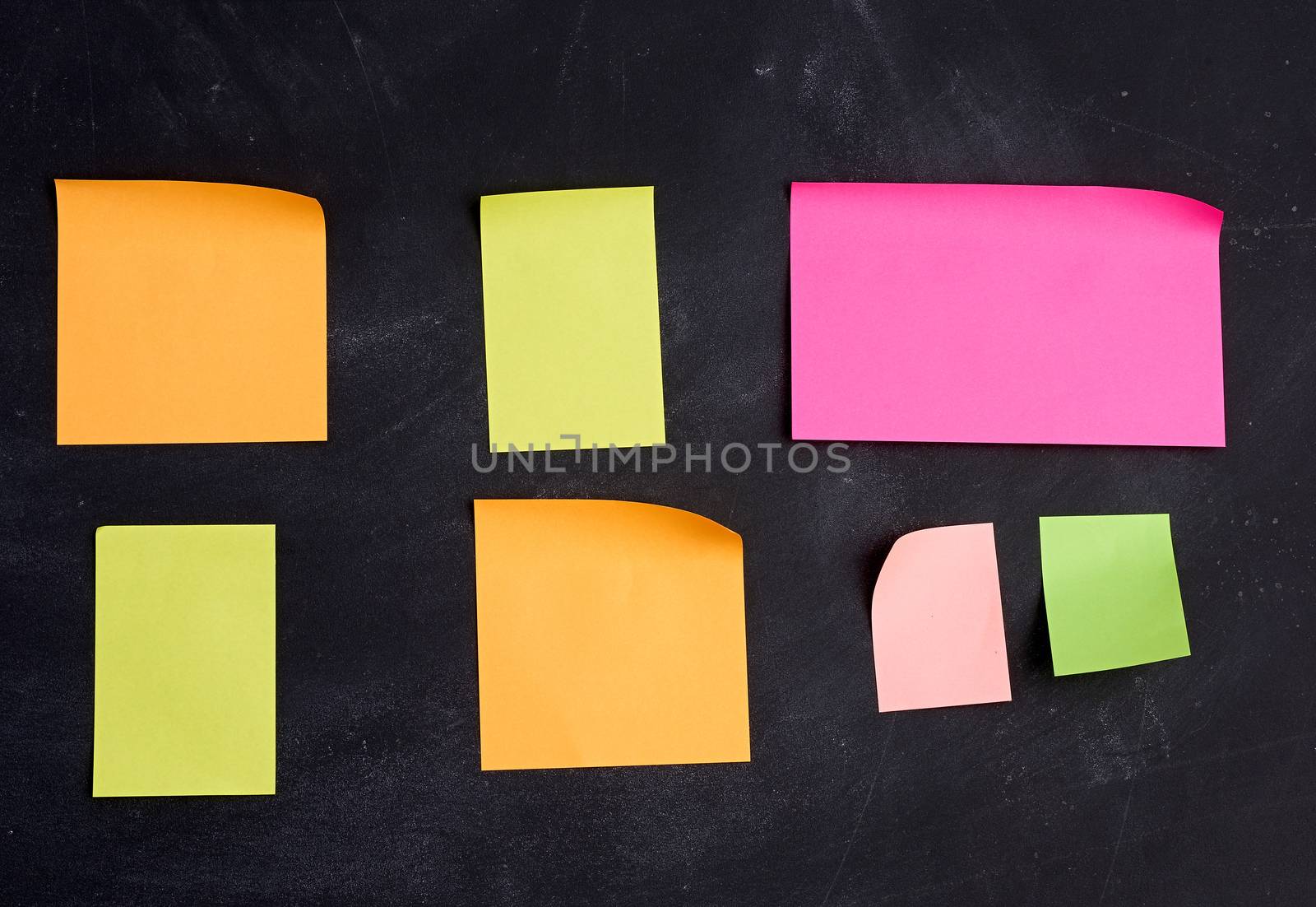empty paper multi-colored stickers are glued on a black board by ndanko