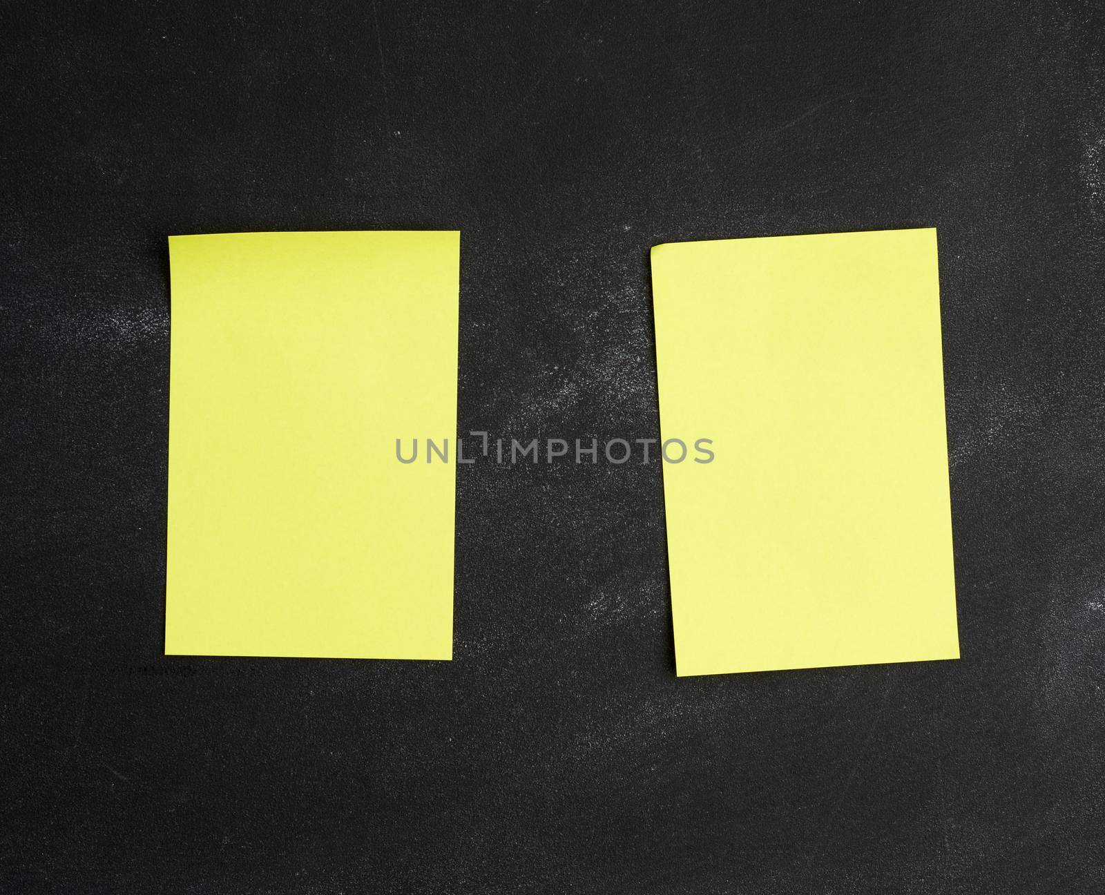 blank yellow paper sticker glued on a black board, place for an inscription, close up