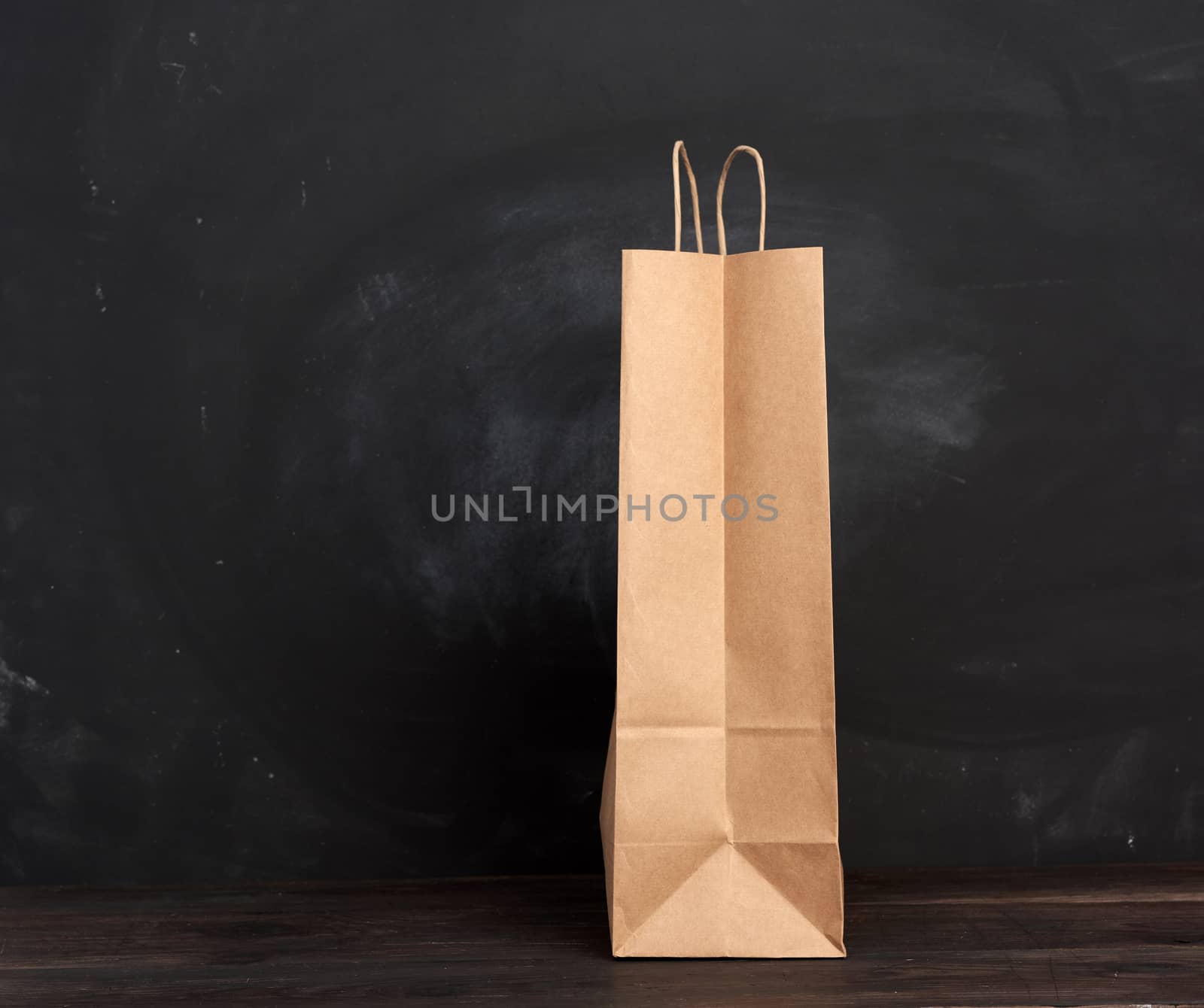 brown paper bag with handles stands on a wooden background by ndanko