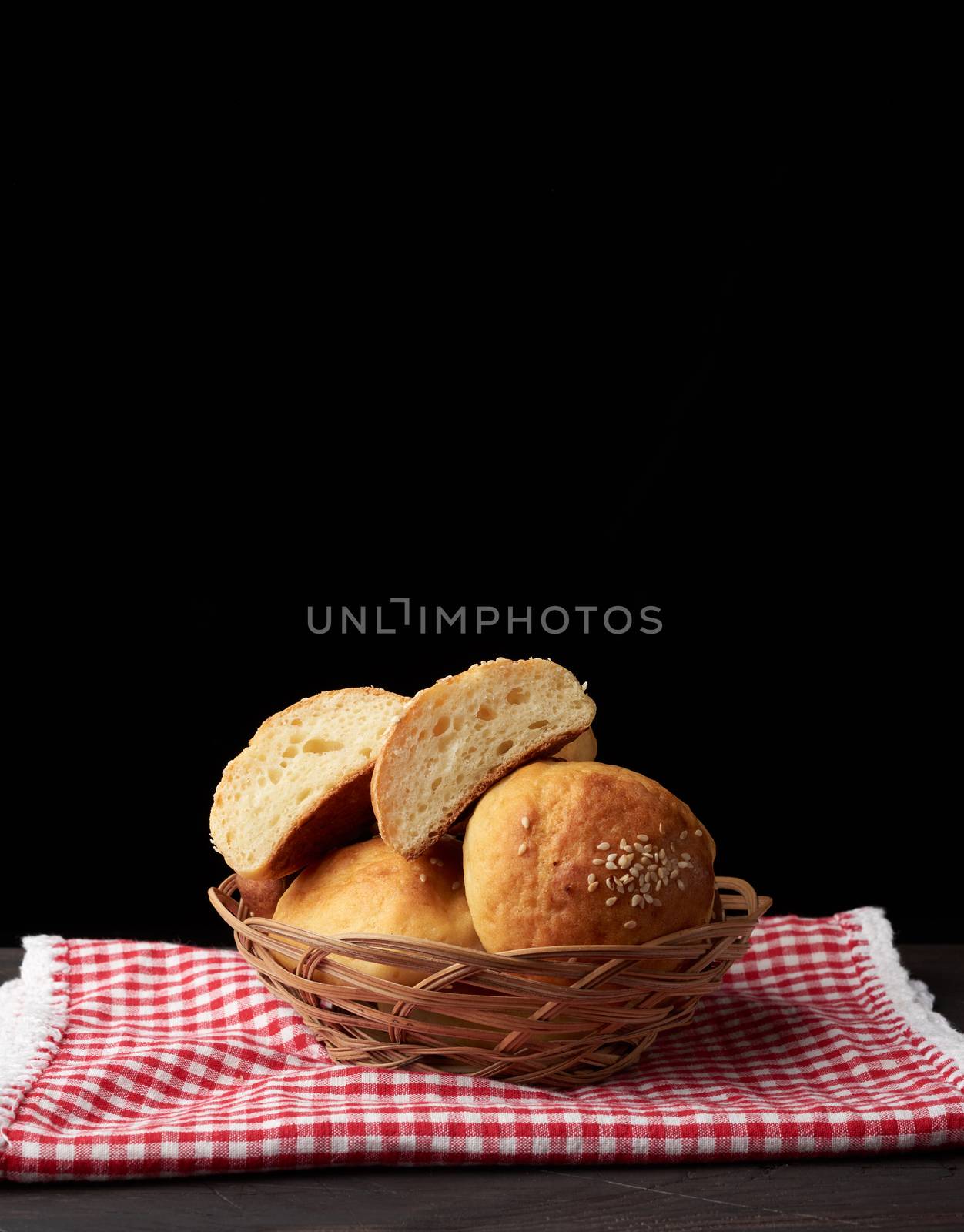baked round bun with sesame seeds, black background, home baking, copy space