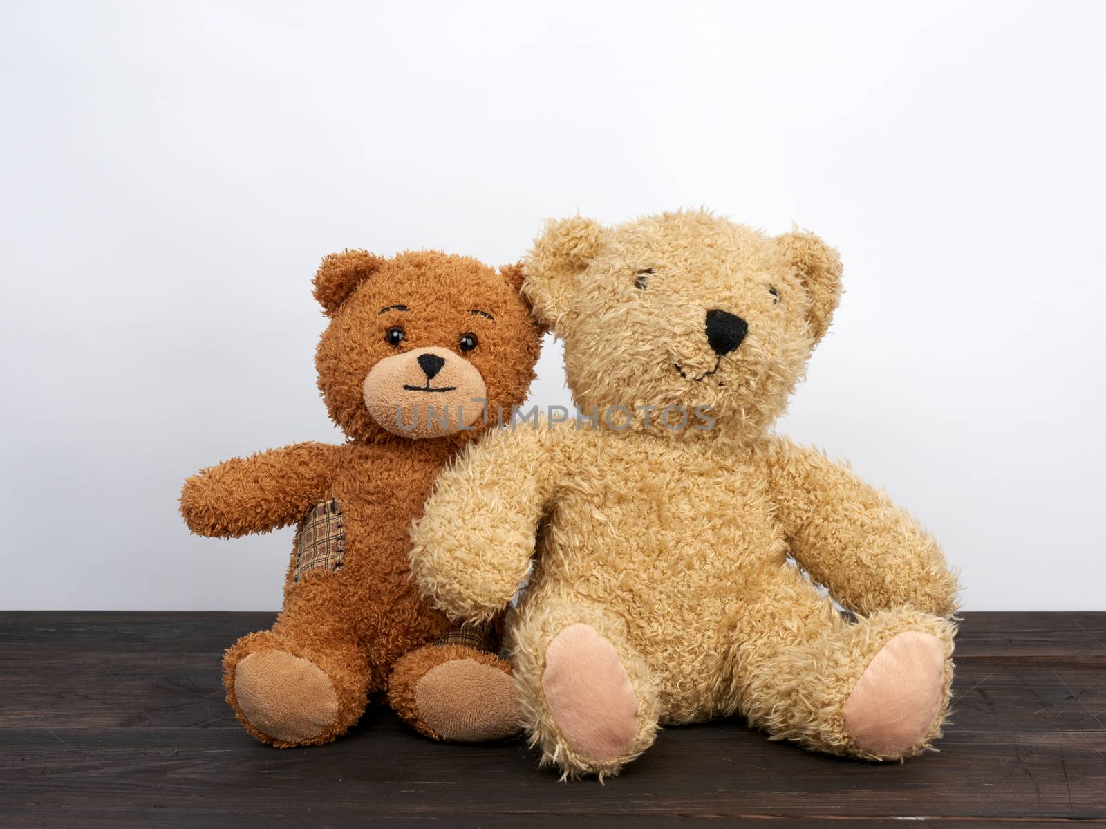 brown teddy bears are sitting on a brown wooden table, white background, friendship concept