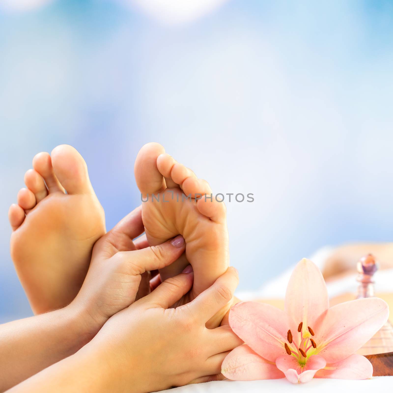 Close up foot reflexology. Podiatrist massaging female foot against colourful background.