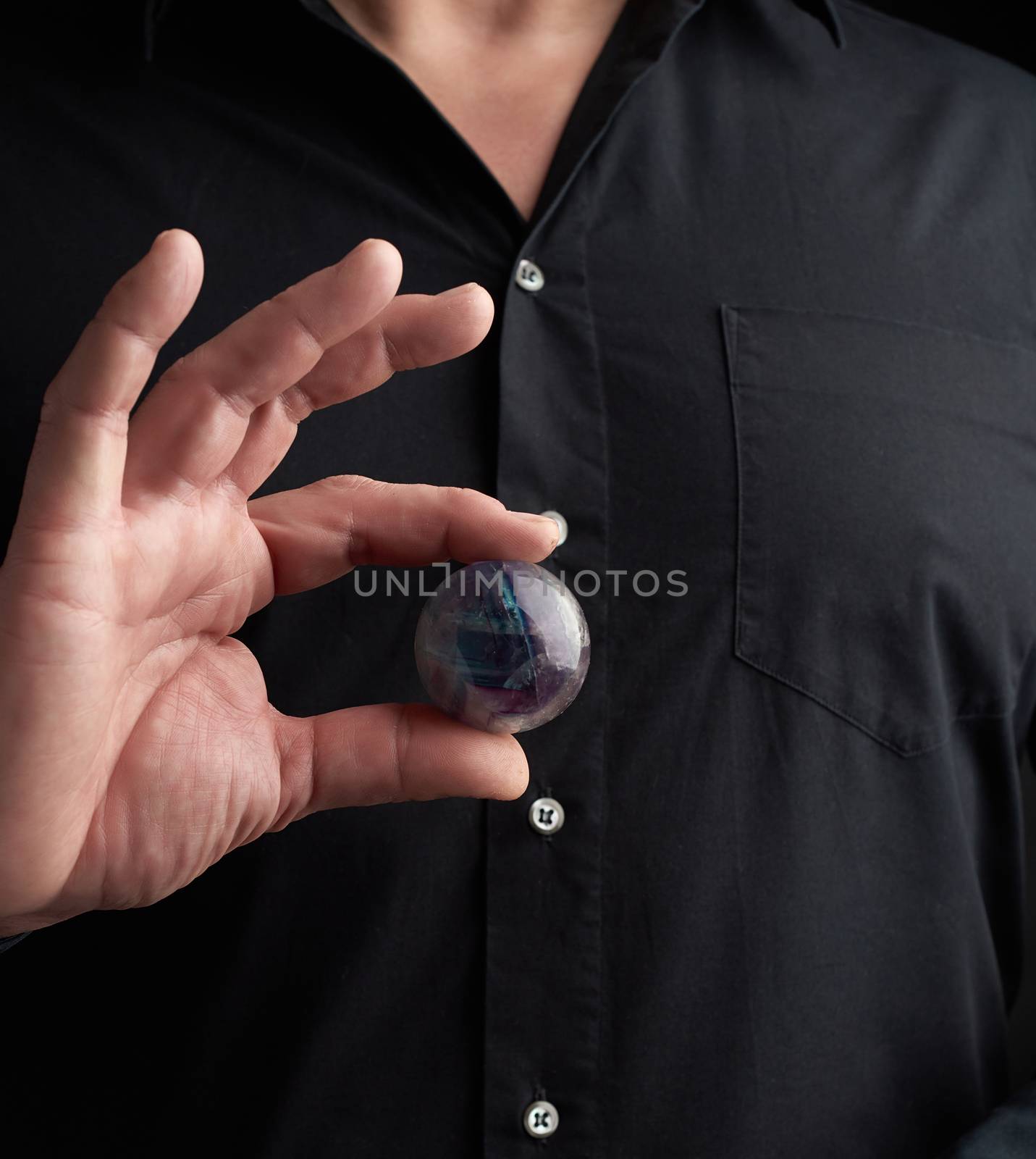 adult man in black clothes holds in his hands a glass magic ball by ndanko