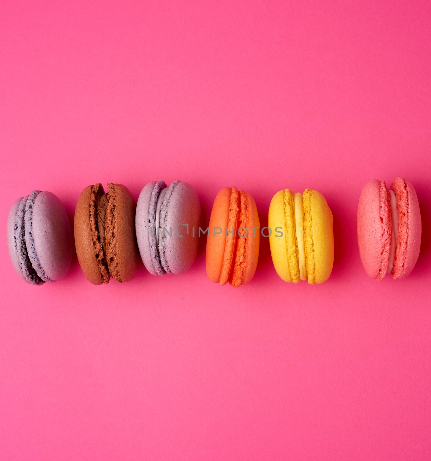 colorful baked macarons almond flour on a pink background by ndanko