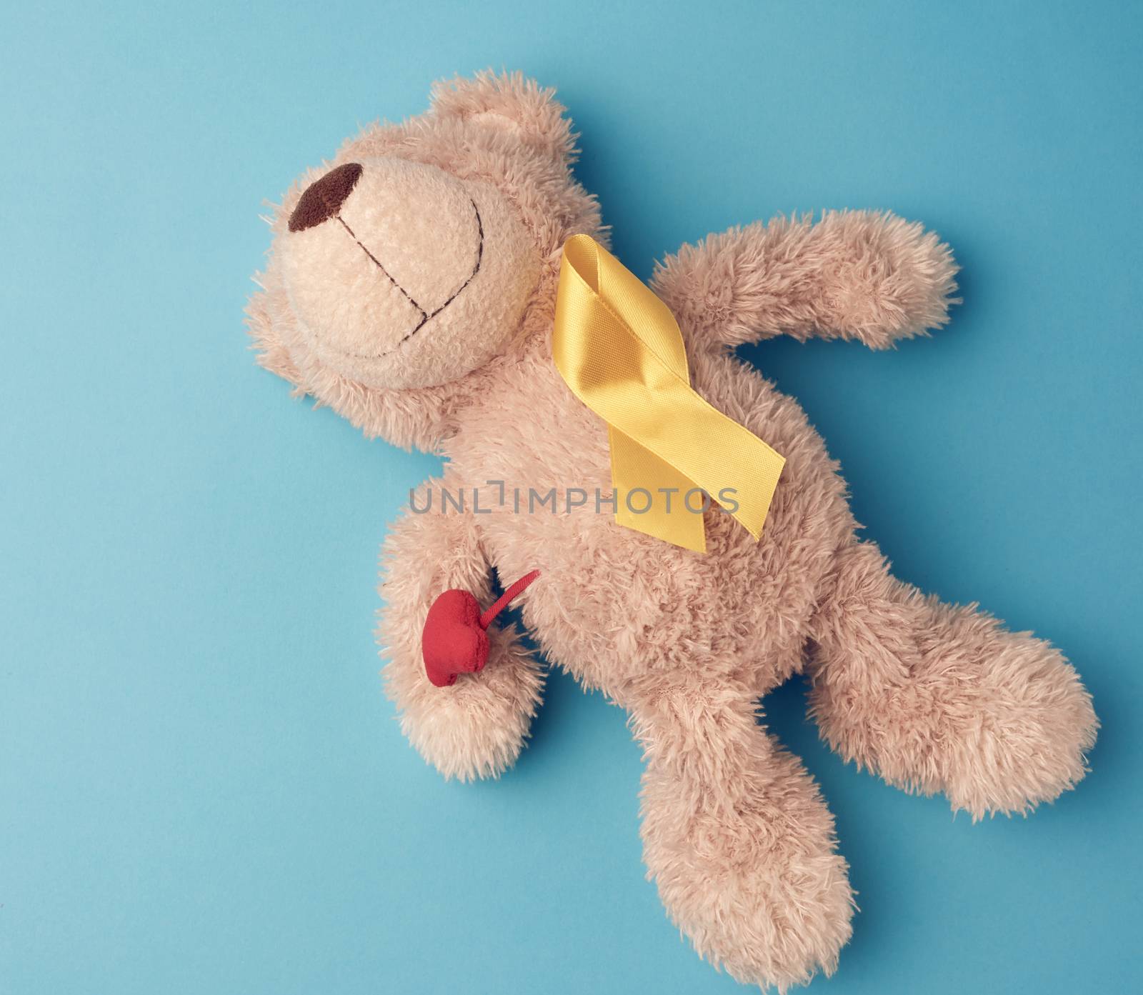 teddy bear holds in his paw a yellow ribbon folded in a loop on  by ndanko