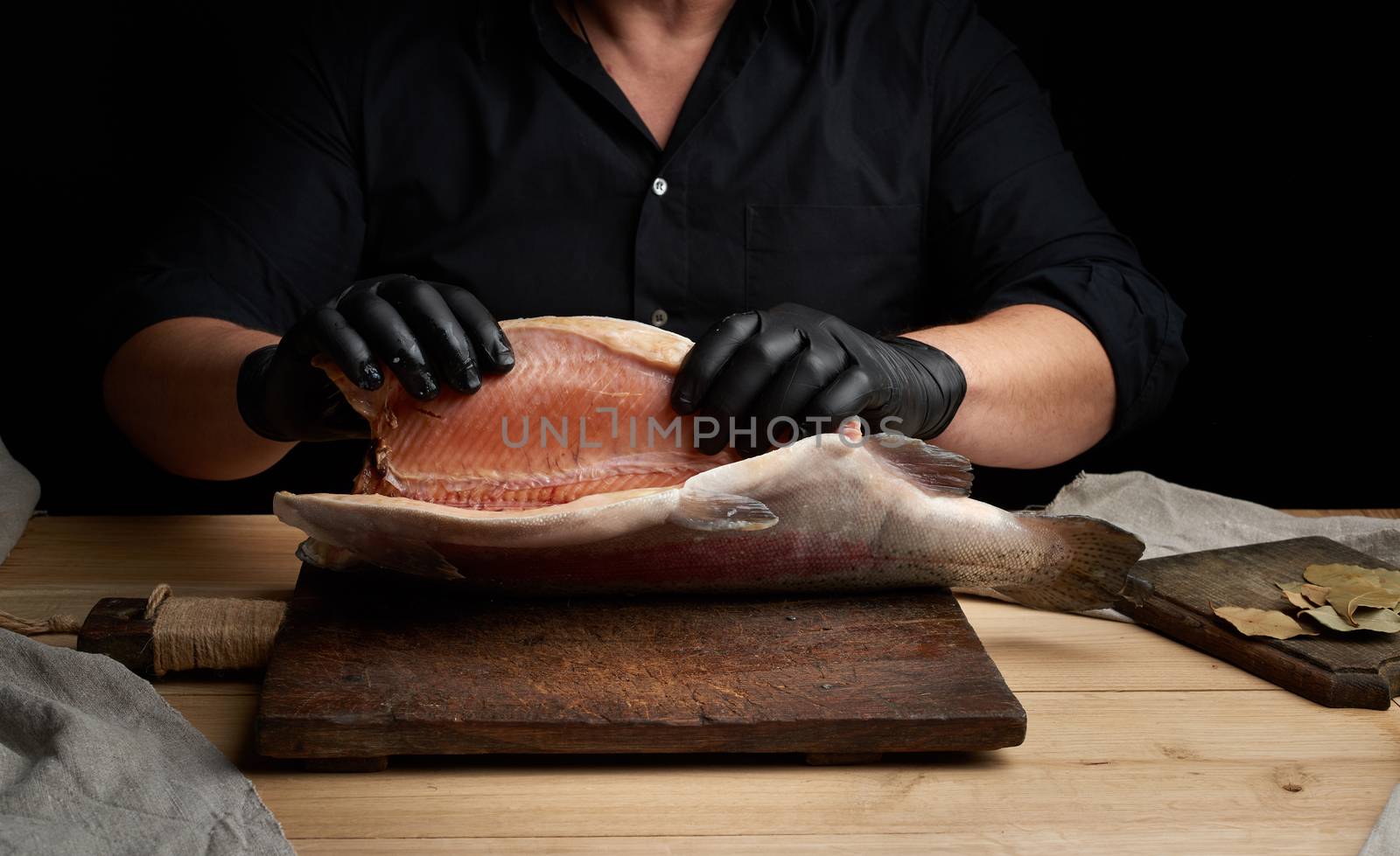 chef in a black shirt and black latex gloves holds a raw carcass by ndanko