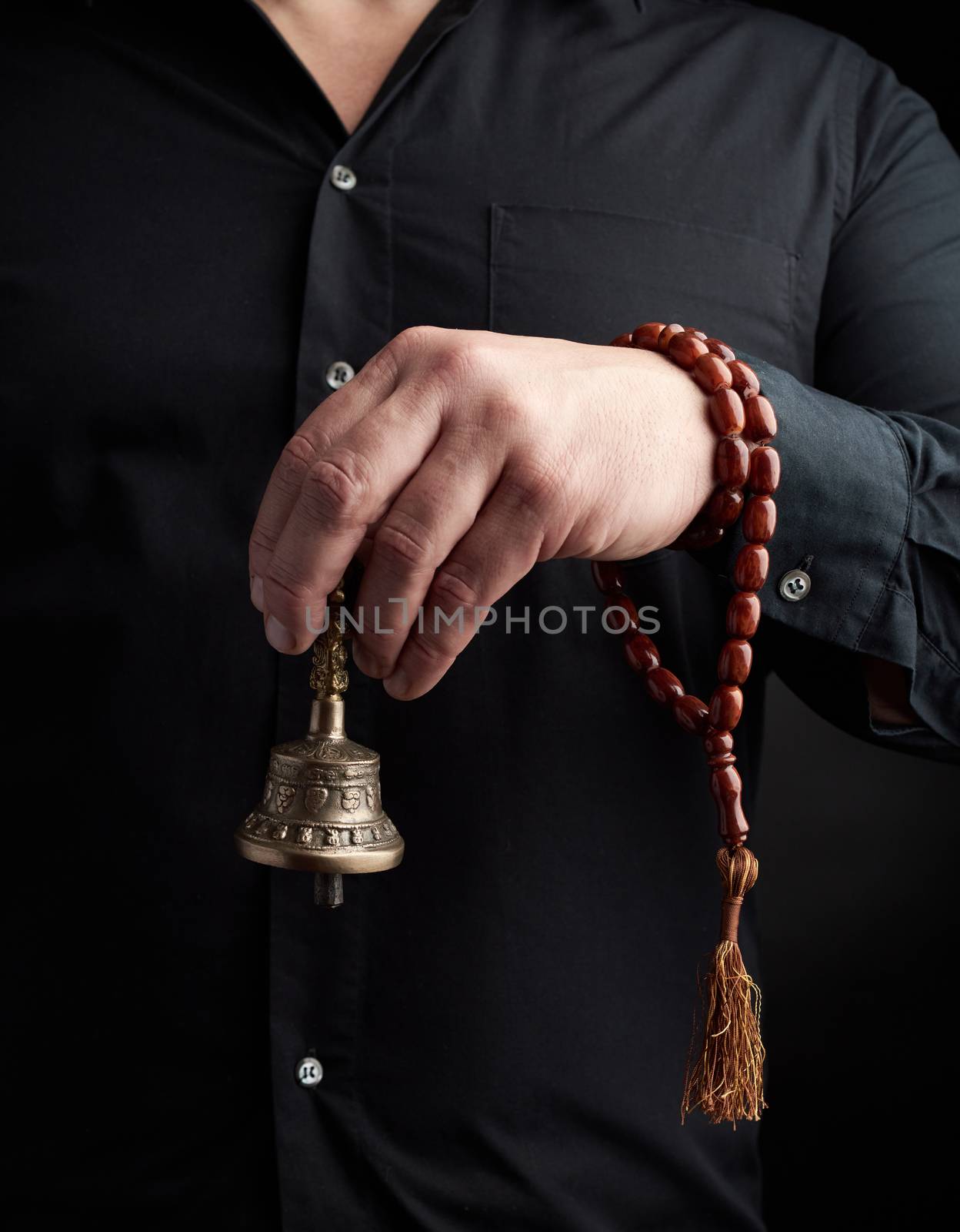 adult man in a black shirt holds a copper Tibetan ritual bell by ndanko