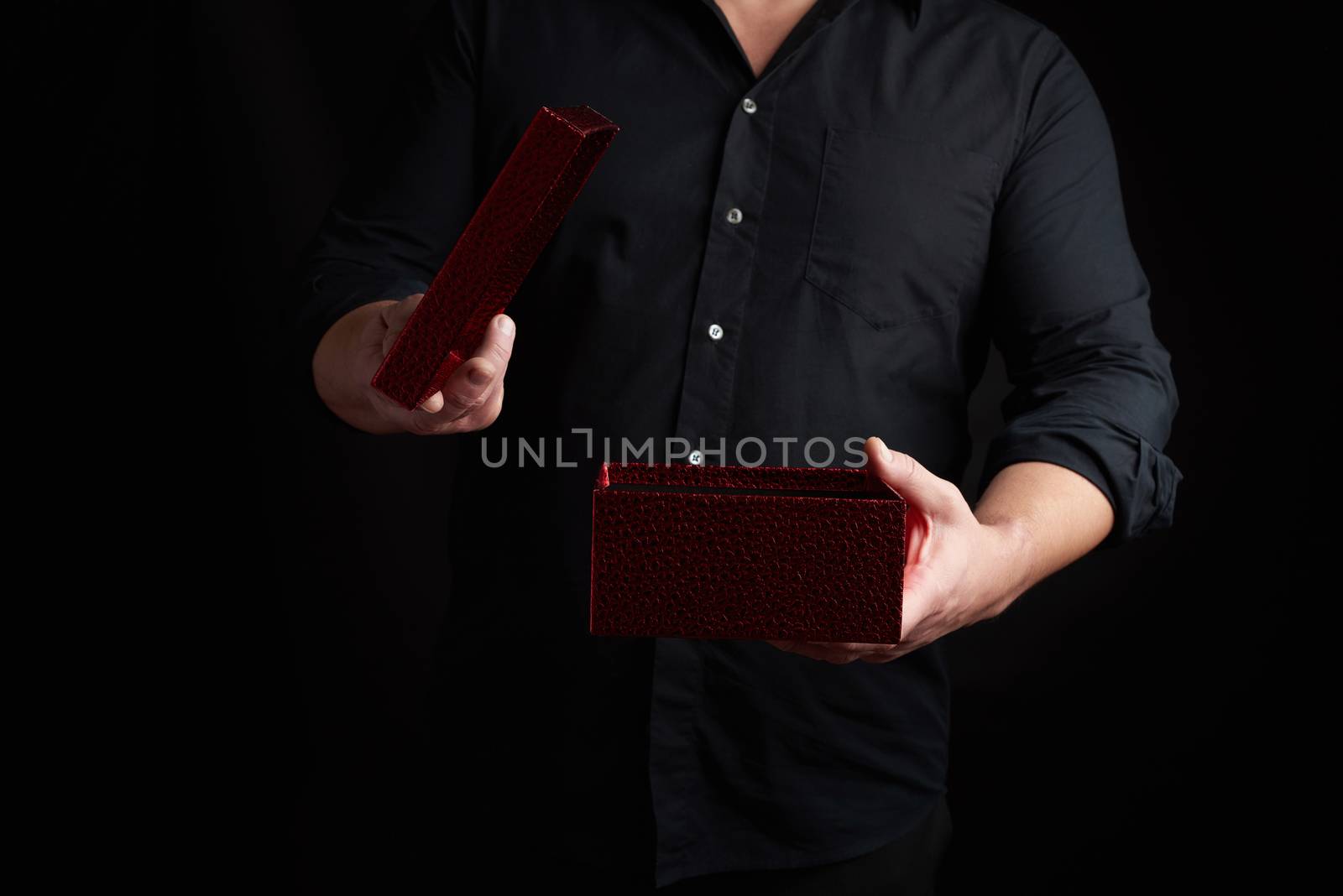 adult man in a black shirt holds an open shiny red cardboard box, concept of surprise and holiday greetings