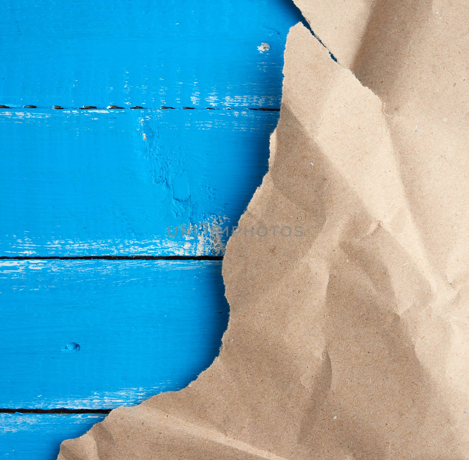 torn piece of paper on blue wooden background, copy space