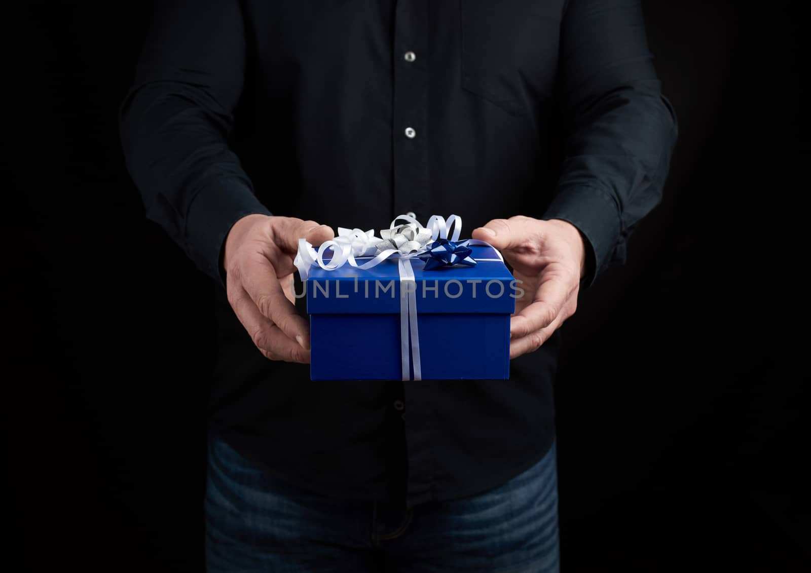 adult man in a black shirt holds a blue square box with a white  by ndanko