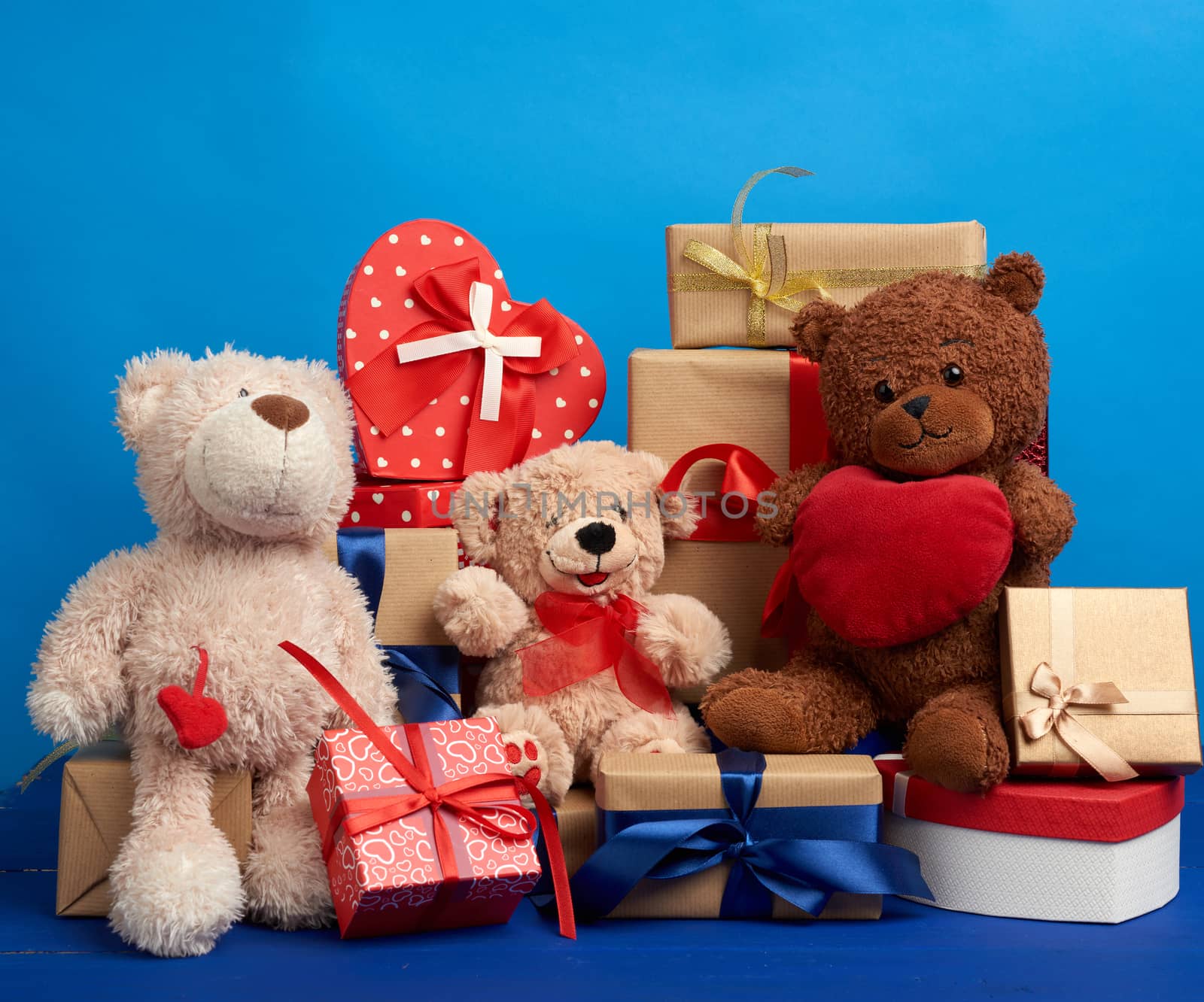 bunch of gifts in boxes tied with silk ribbons and soft teddy bears on a blue background, festive backdrop for birthday, Christmas