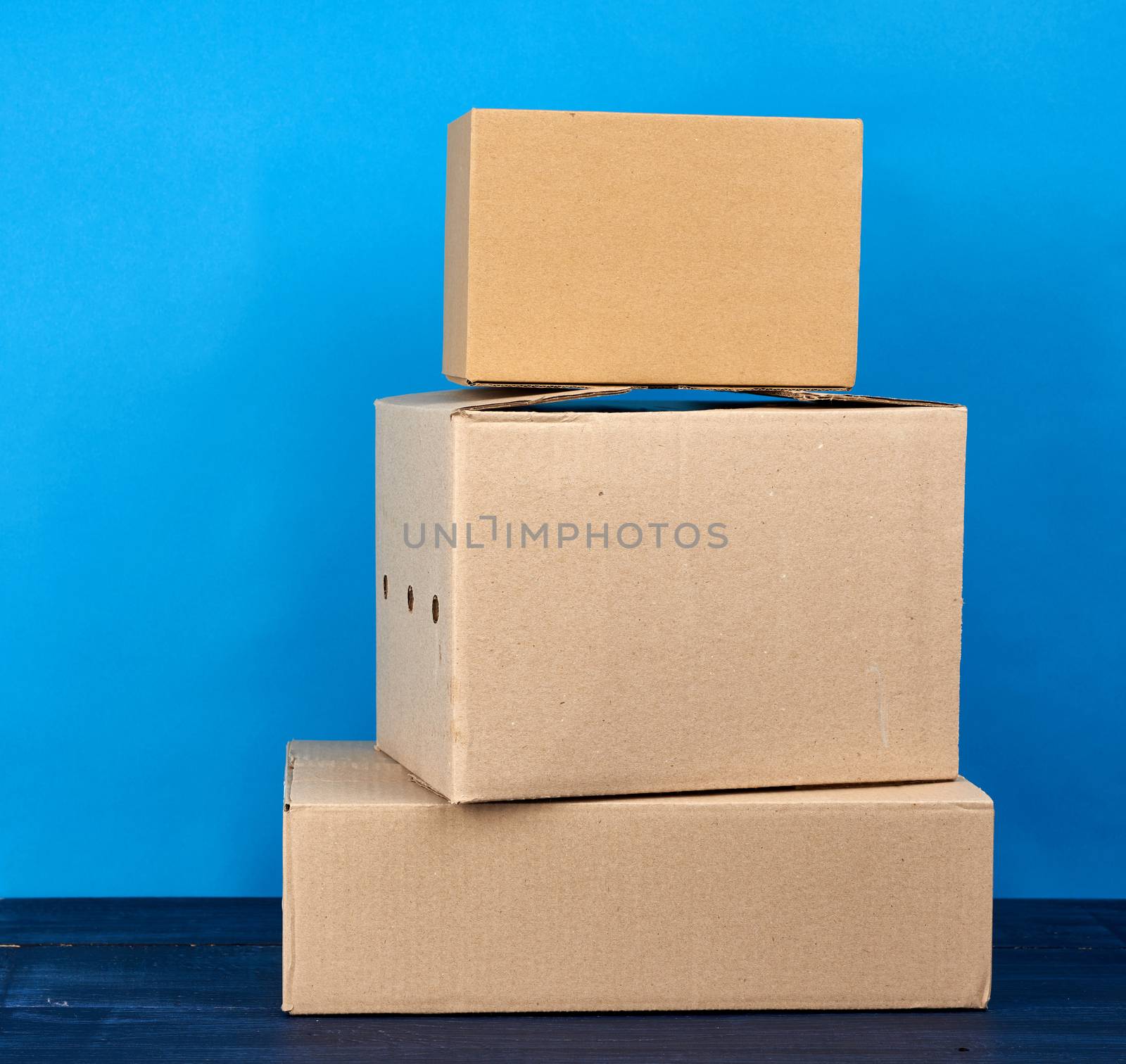stack of cardboard boxes of brown kraft paper on a blue wooden t by ndanko